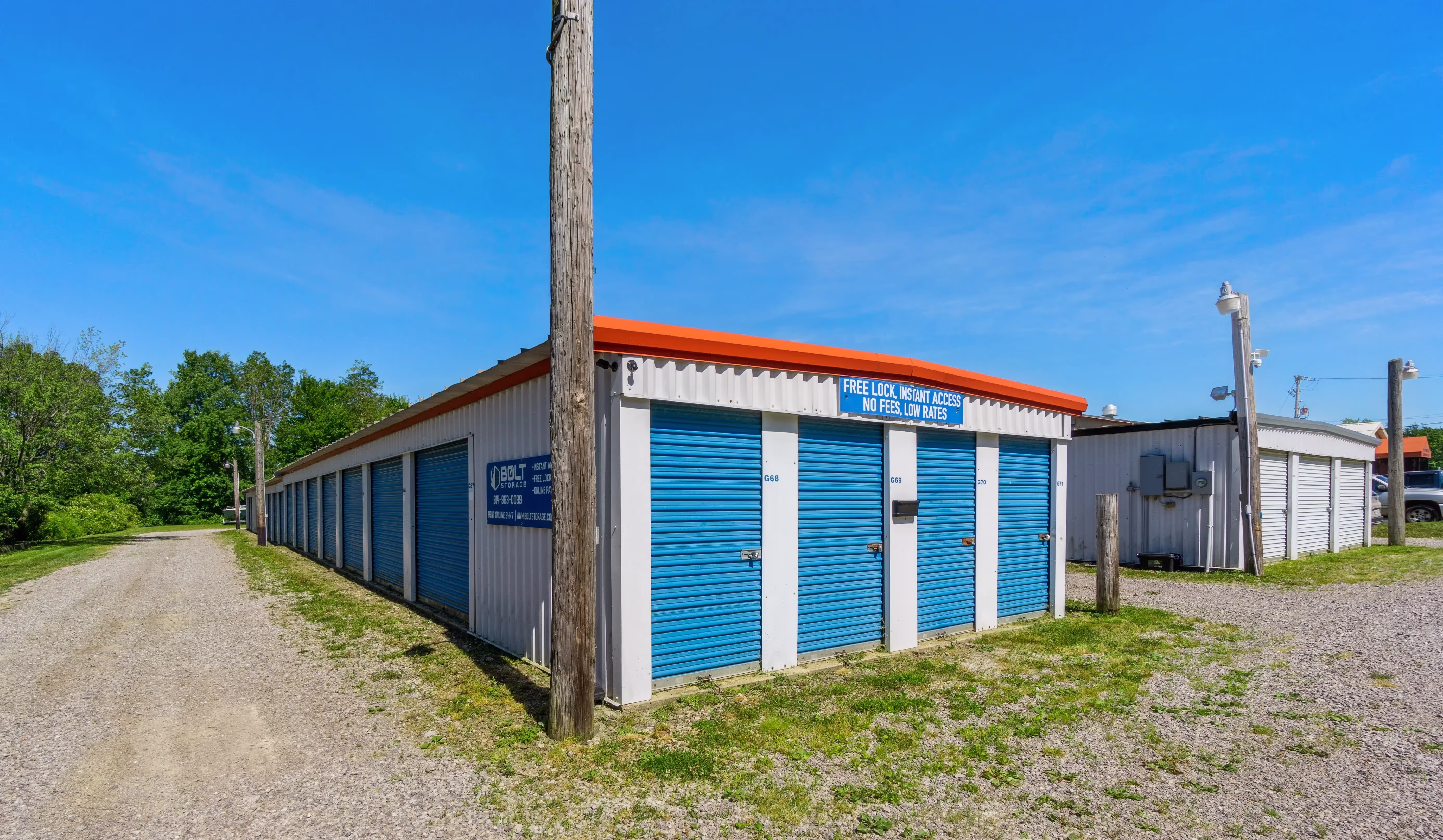 orner perspective of blue roll up storage units beneath a red roof with utility pole visible at our Erie PA facility