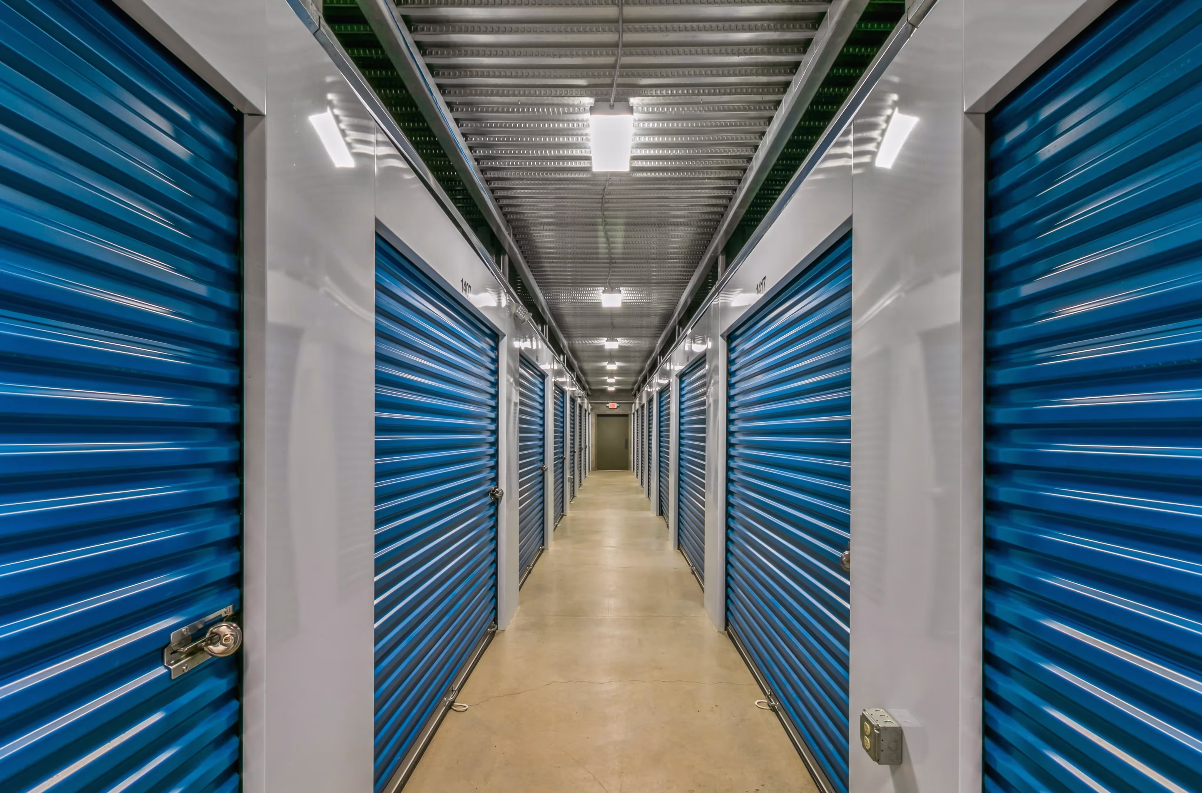 Clean climate controlled storage hallway with blue roll up doors in Ithaca NY