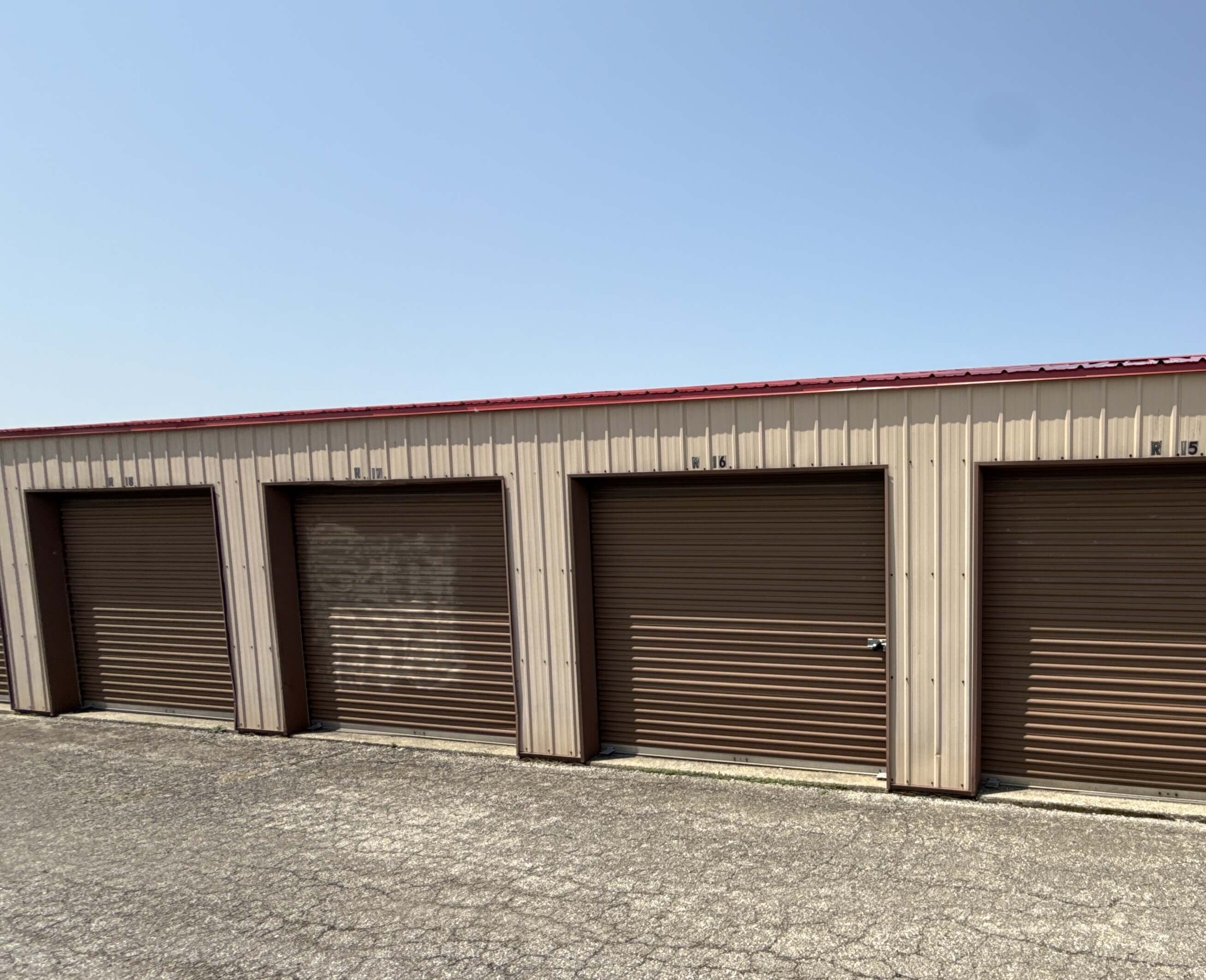 Exterior view of storage units with brown roll up doors along gravel driveway in Kokomo IN