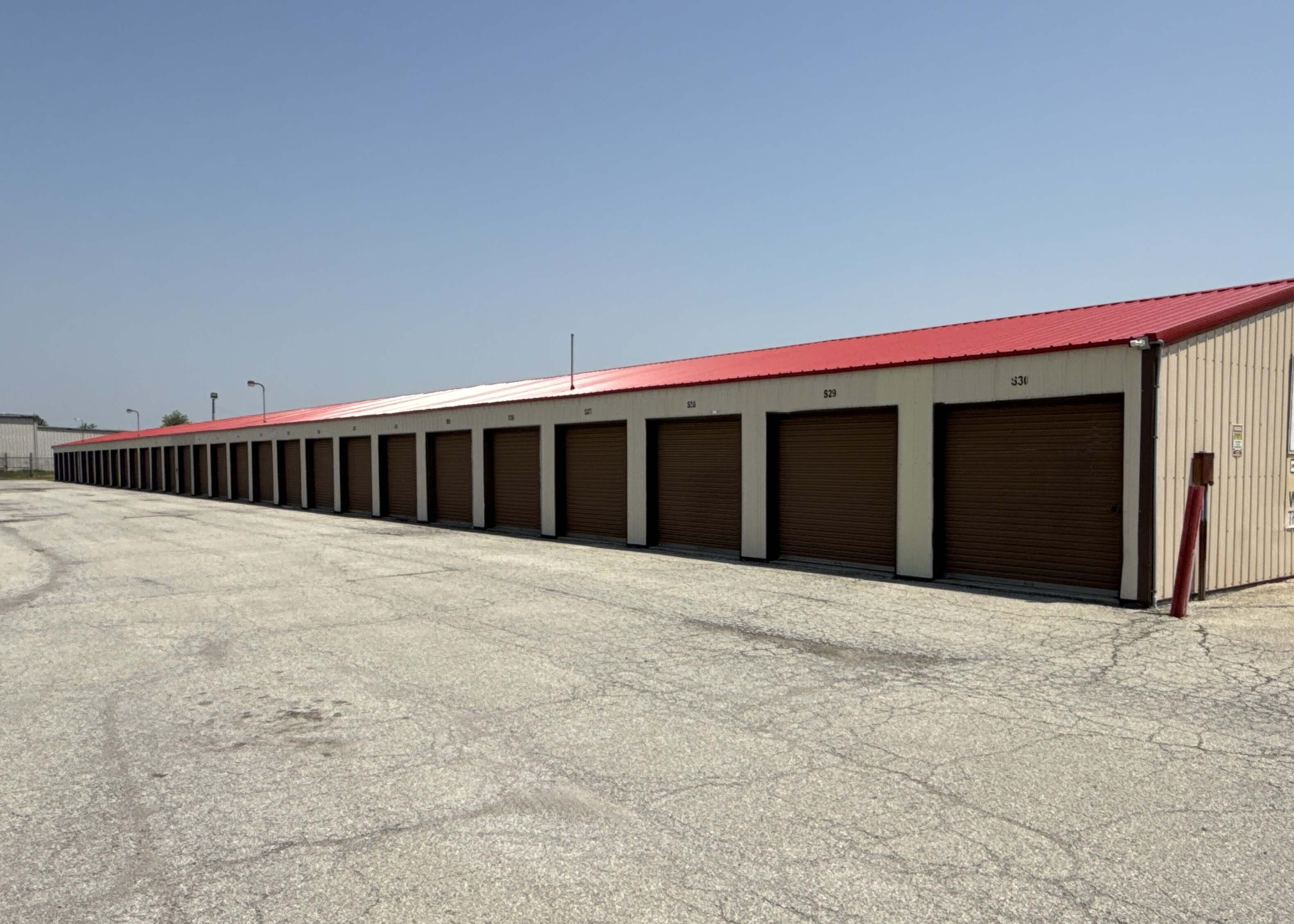 Angled view of drive up storage buildings with brown doors and red roof in Kokomo IN