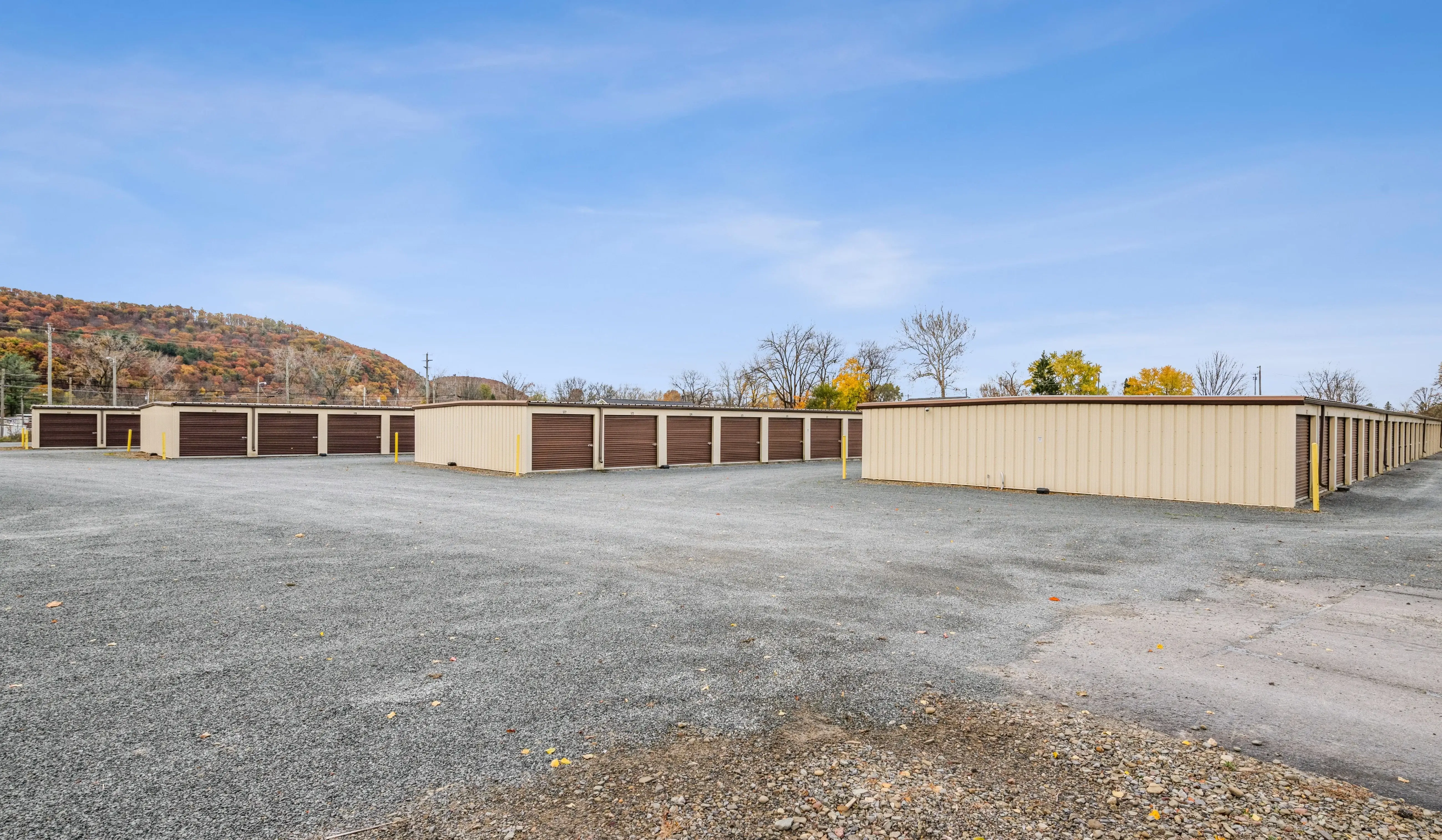 Drive up storage buildings with brown doors and open parking area in Horseheads NY