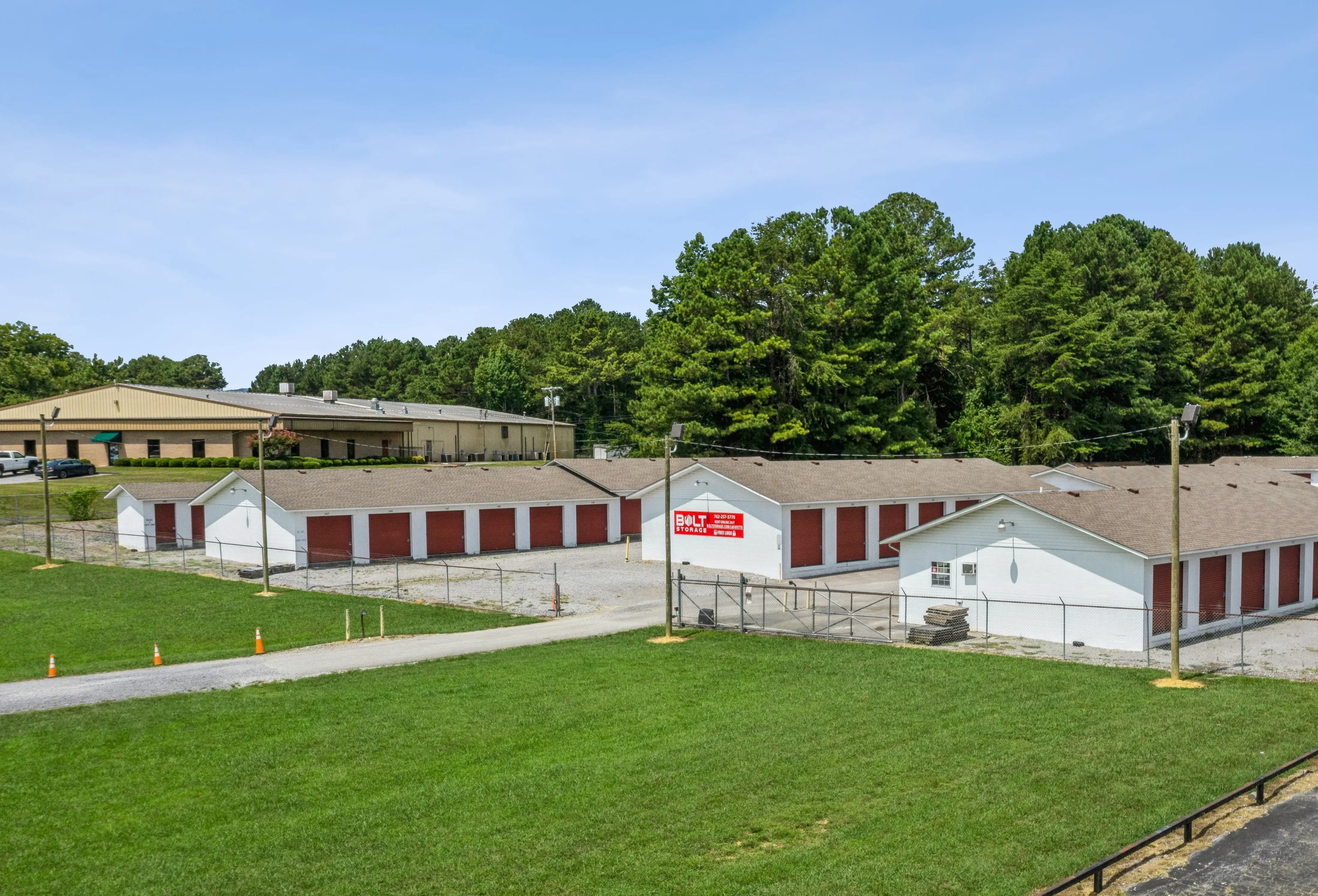 Drive up storage buildings with red roll up doors and grassy surroundings in LaFayette GA