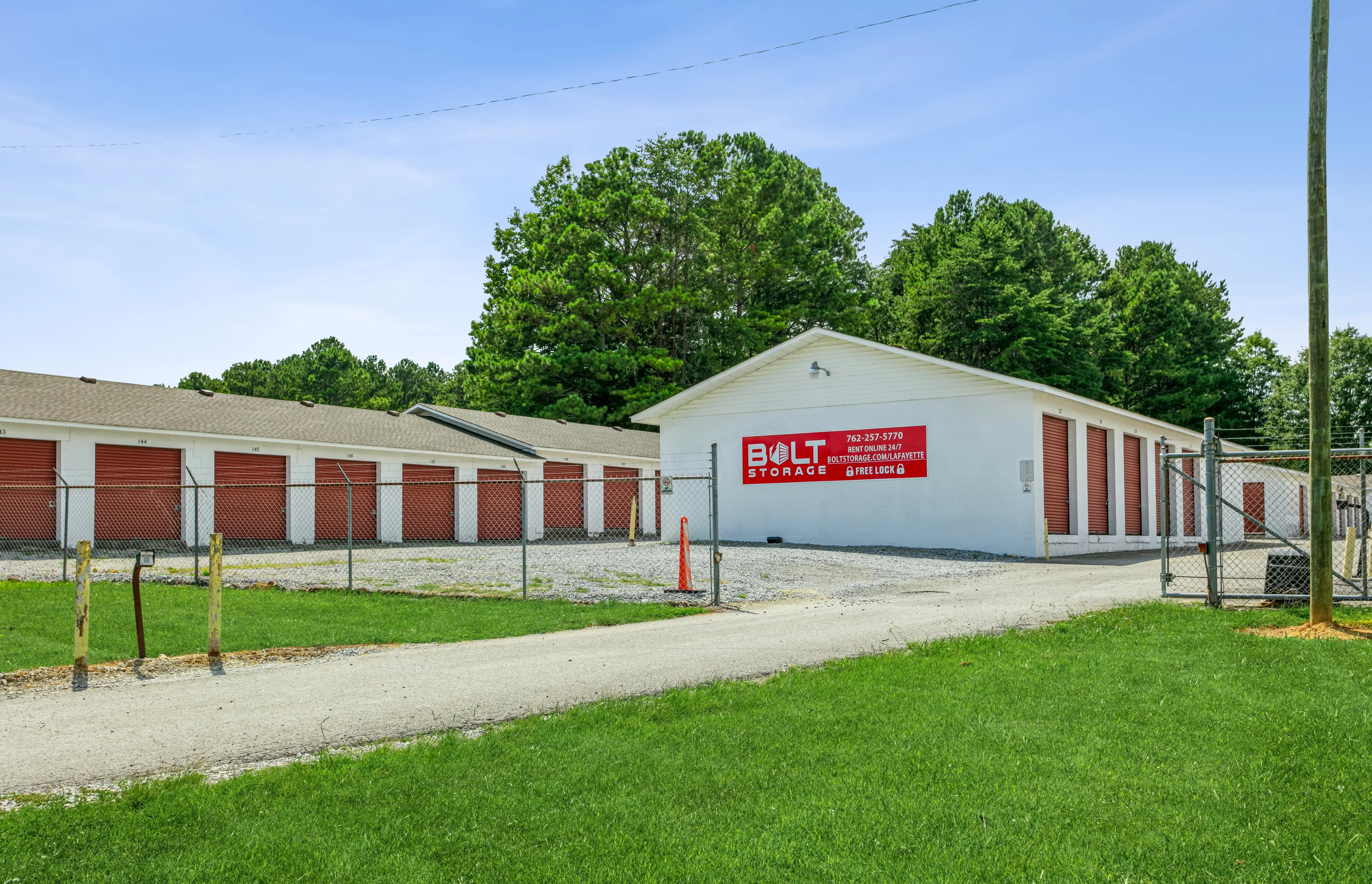 Angled view of storage buildings with red roll up doors and gravel access lanes in LaFayette GA