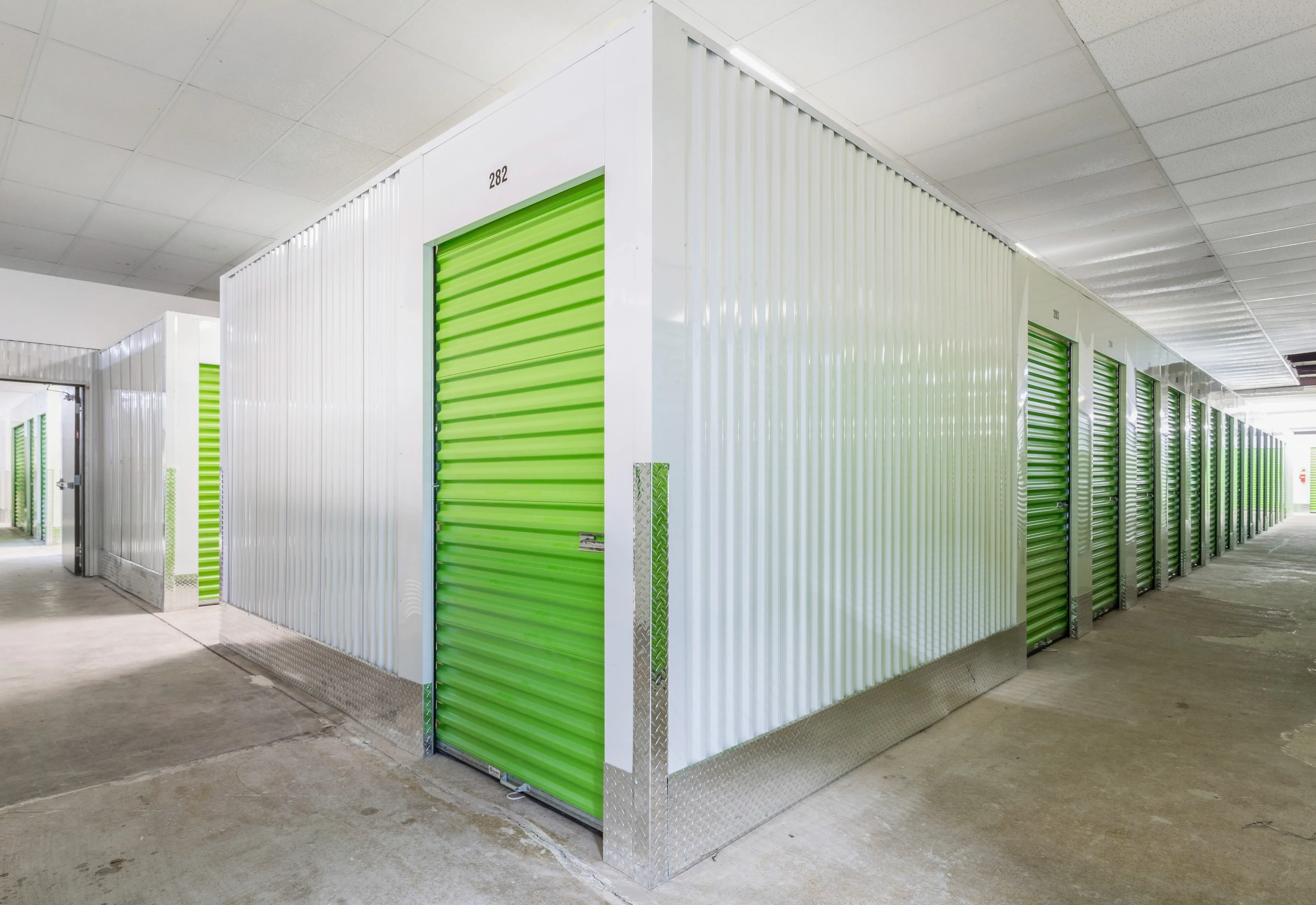 Interior hallway of climate controlled storage units with green doors at our Milledgeville GA facility