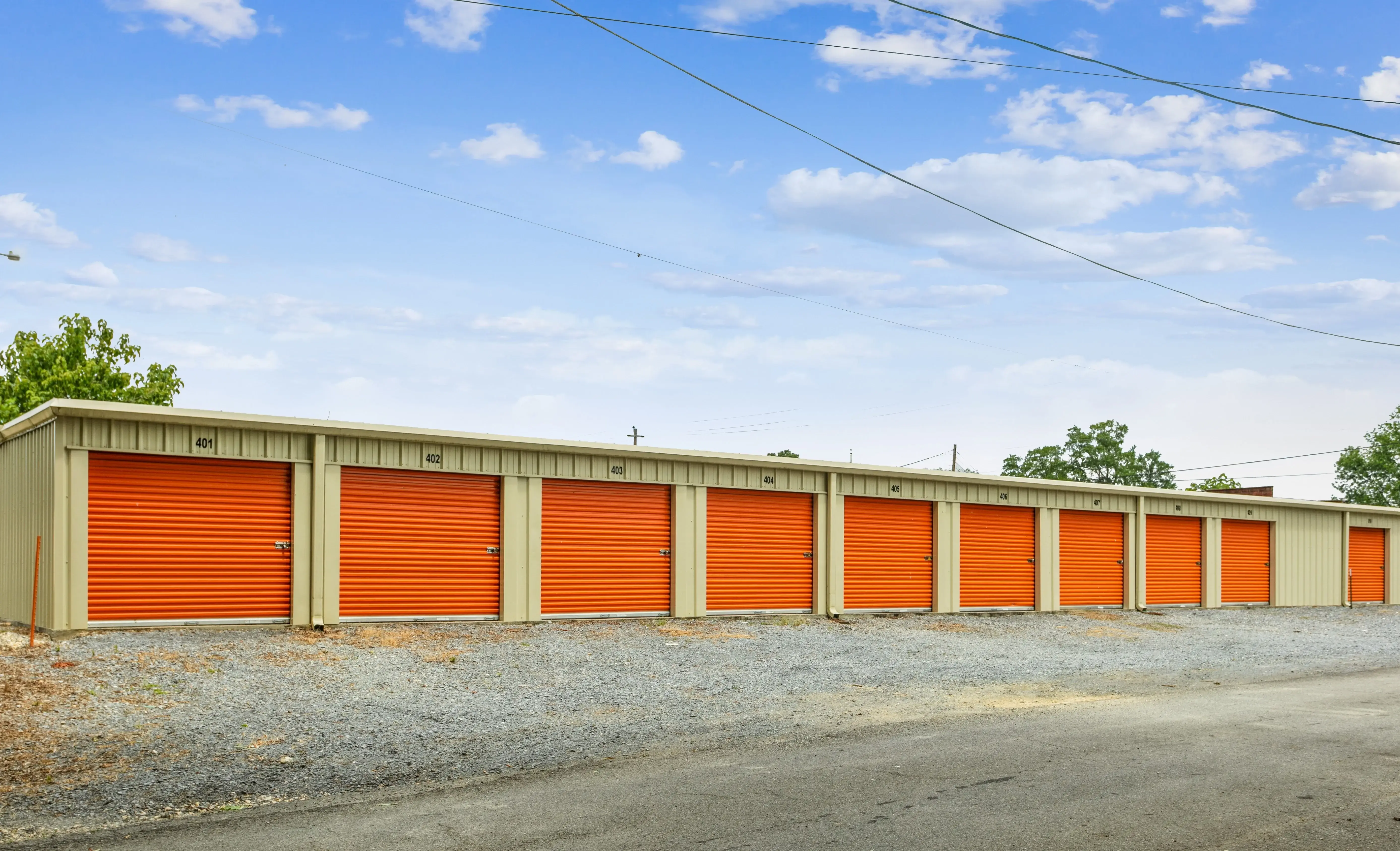 Exterior view of long row of storage units with orange roll up doors in Lyerly GA