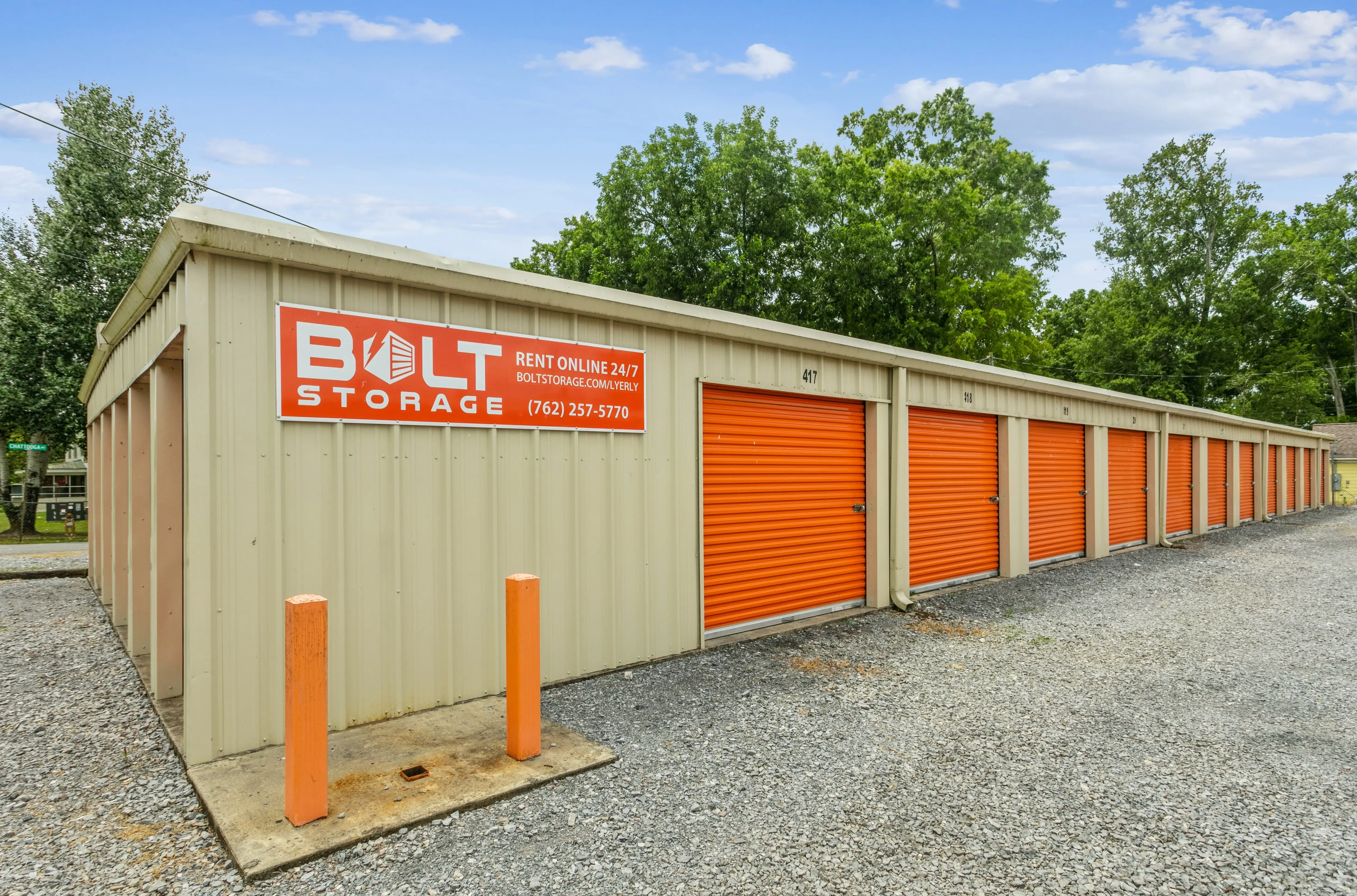 Front corner view of storage building with orange doors and facility signage in Lyerly GA