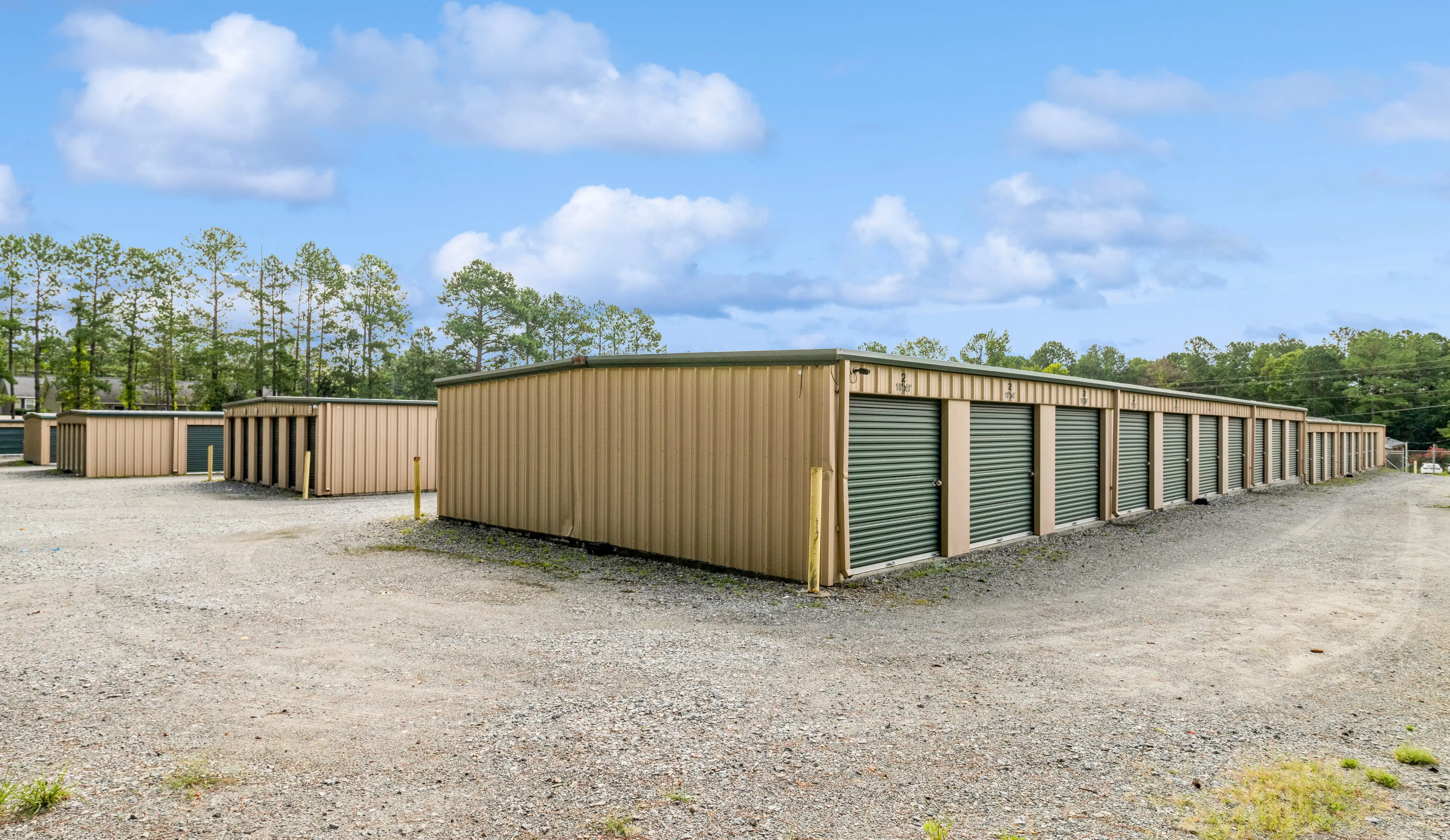 Angled exterior view of storage buildings with green roll up doors in Milledgeville GA
