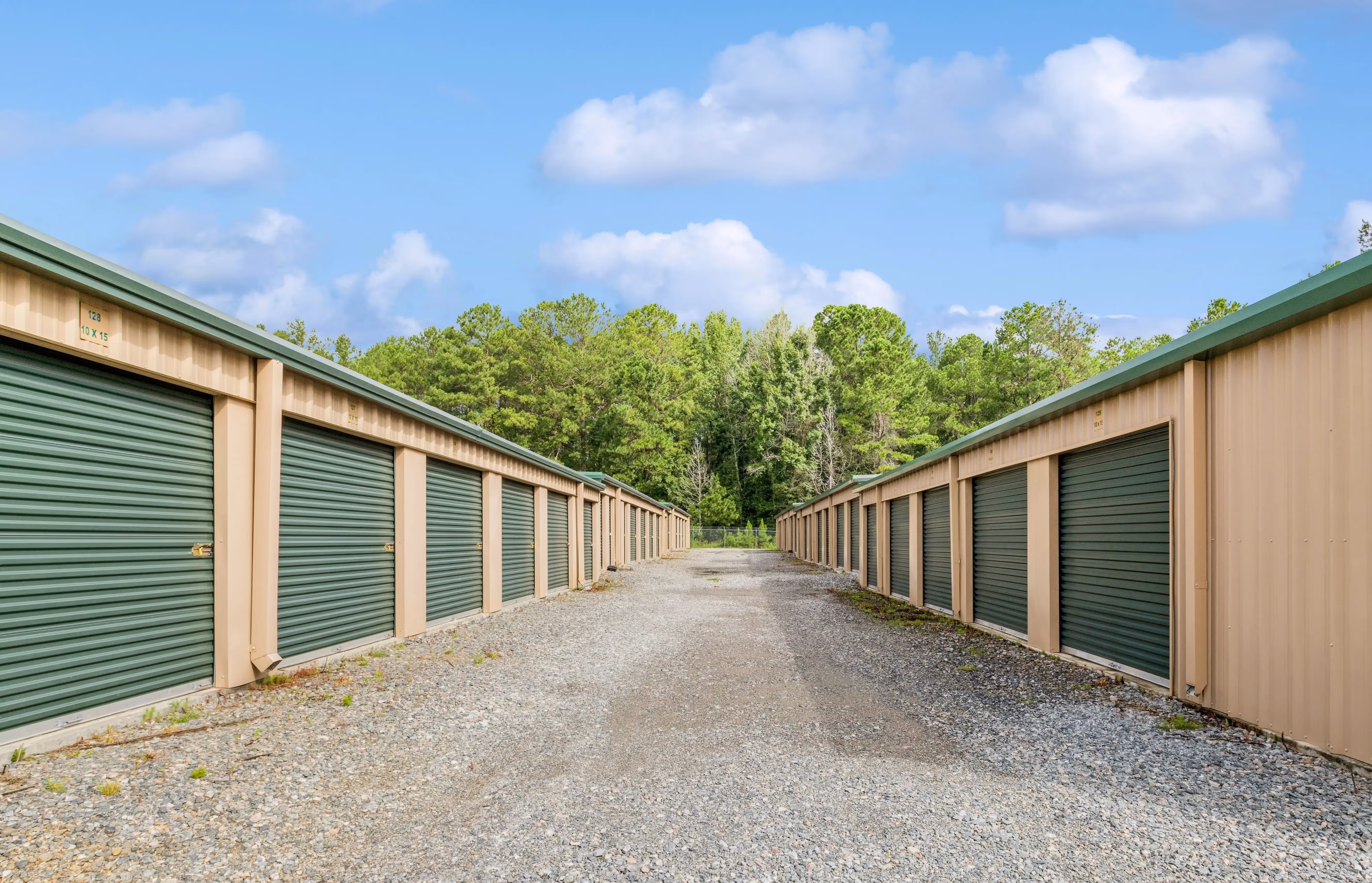 Drive up storage units with green doors along gravel access lanes at our Milledgeville GA location