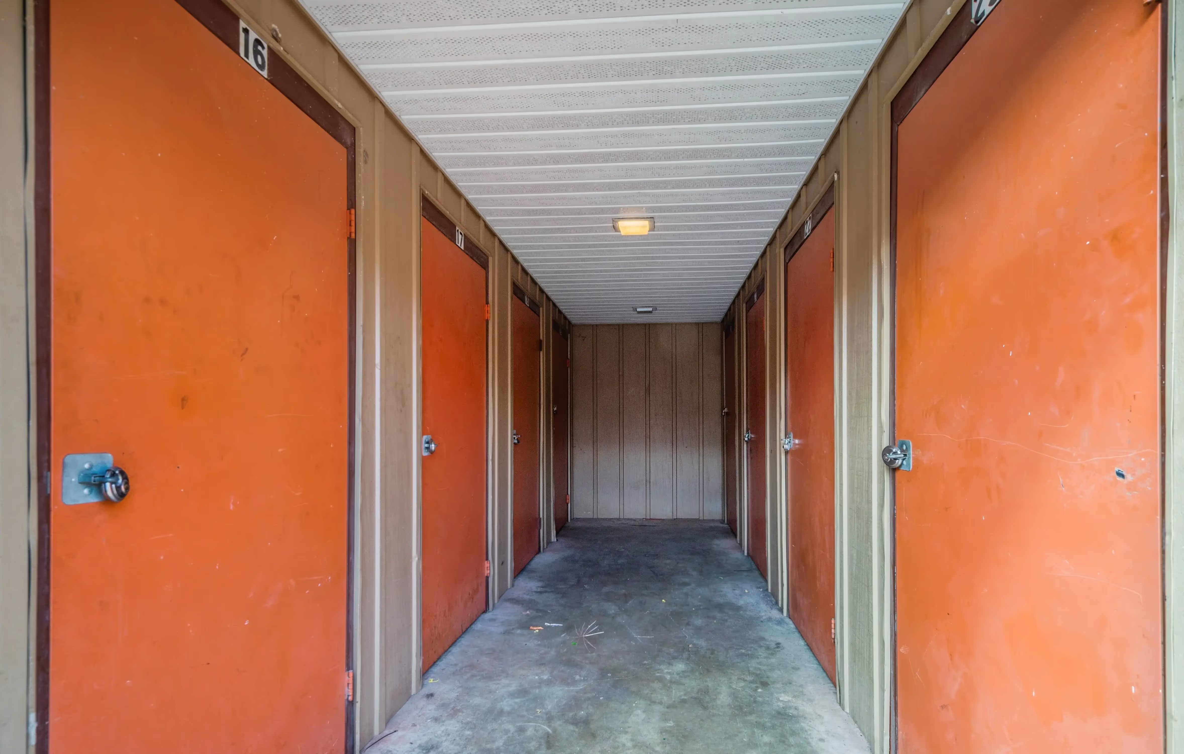 Interior hallway of storage units with orange roll up doors at our Peru IN facility