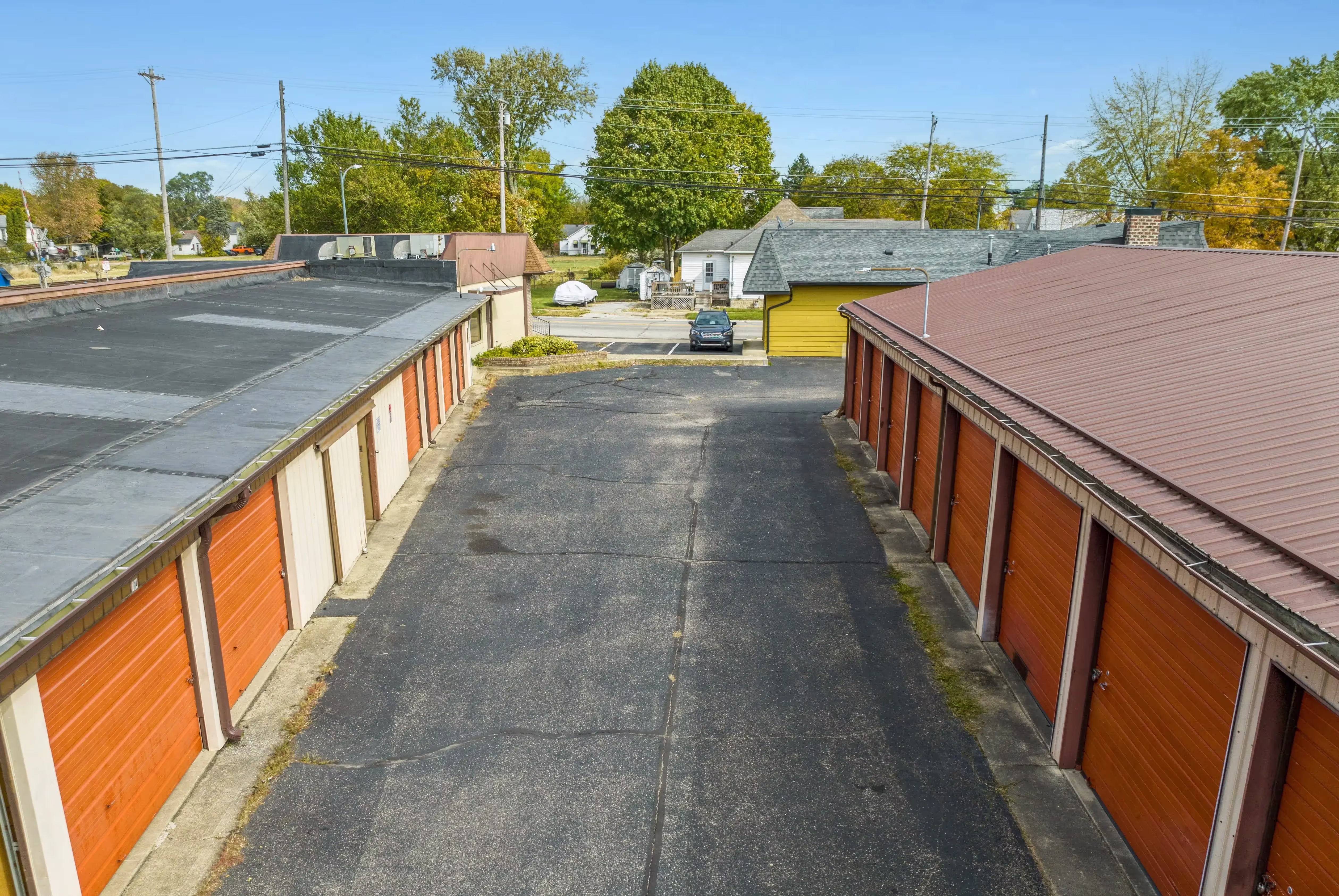 Elevated view of drive up storage buildings with orange doors and paved access lanes in Peru IN
