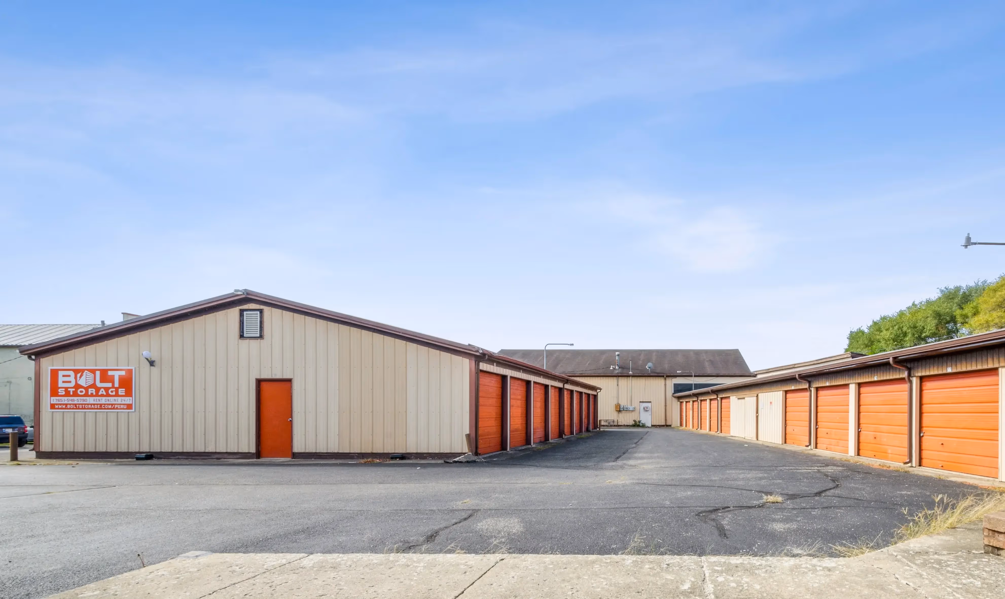 Exterior view of drive up storage units with orange roll up doors at our Peru IN location