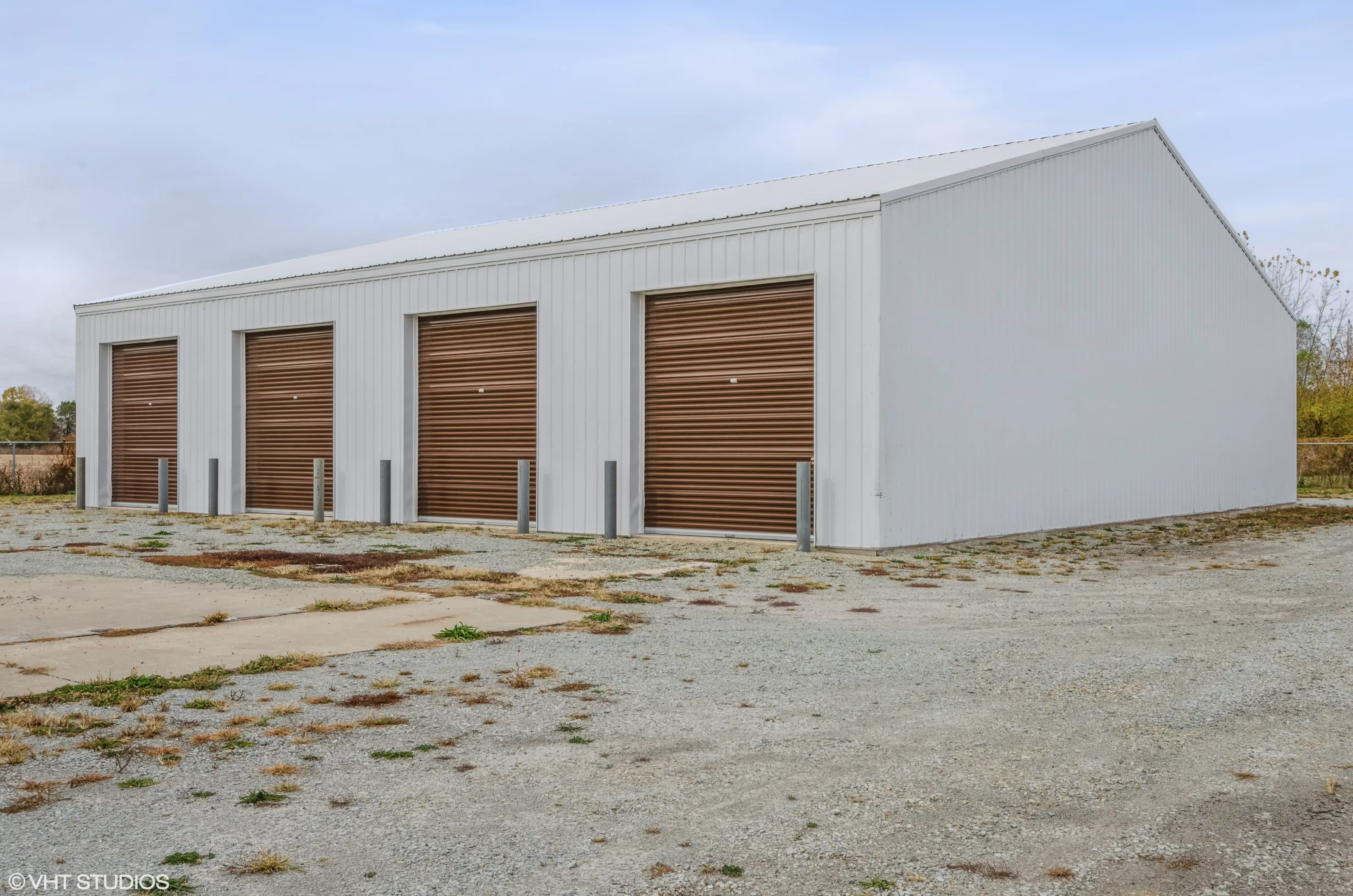 Exterior view of drive up storage units with brown roll up doors and a wide gravel lot at our Peru IN location