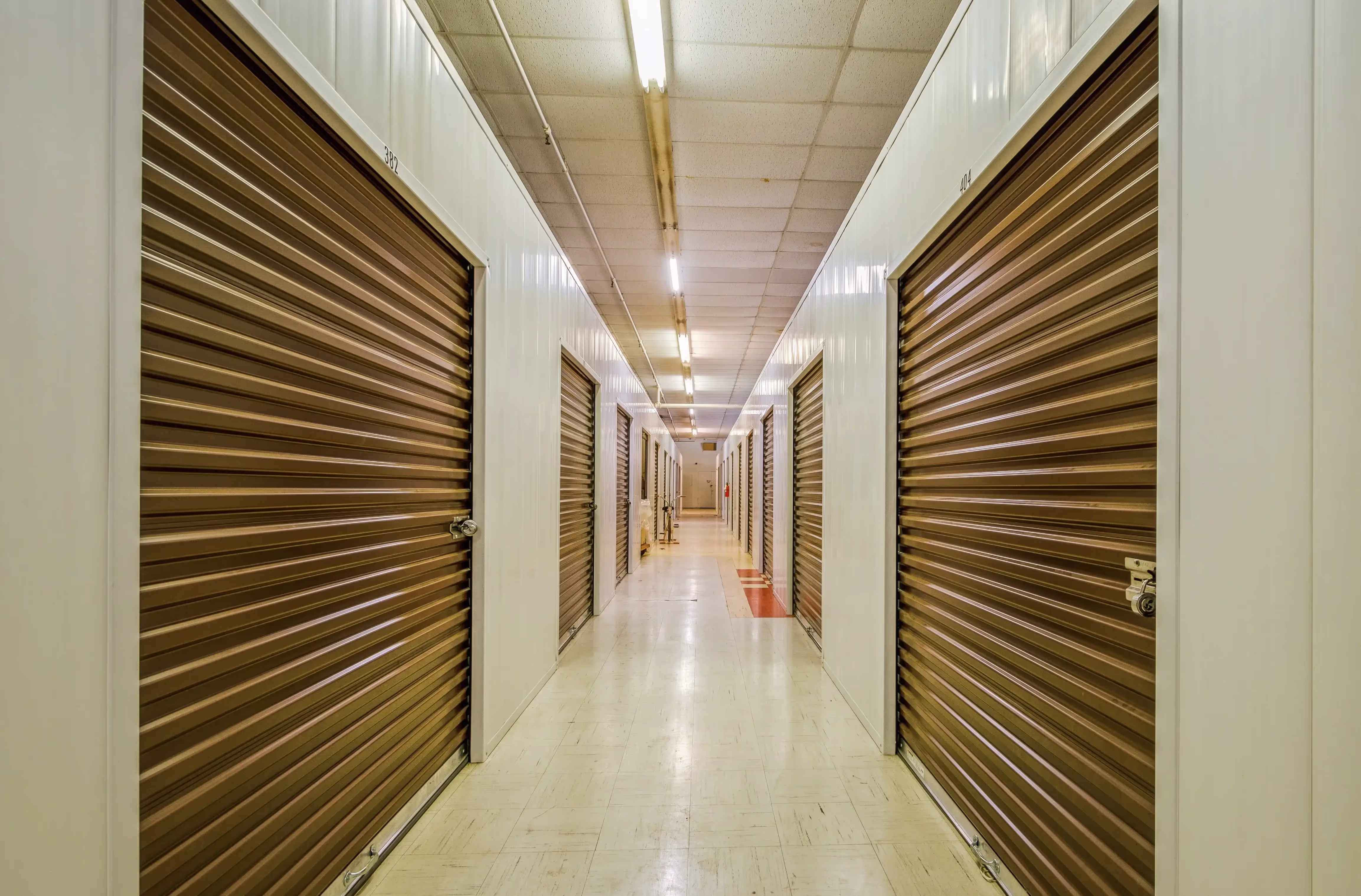 Bright interior hallway lined with brown roll up storage doors and polished floors at our Peru IN facility