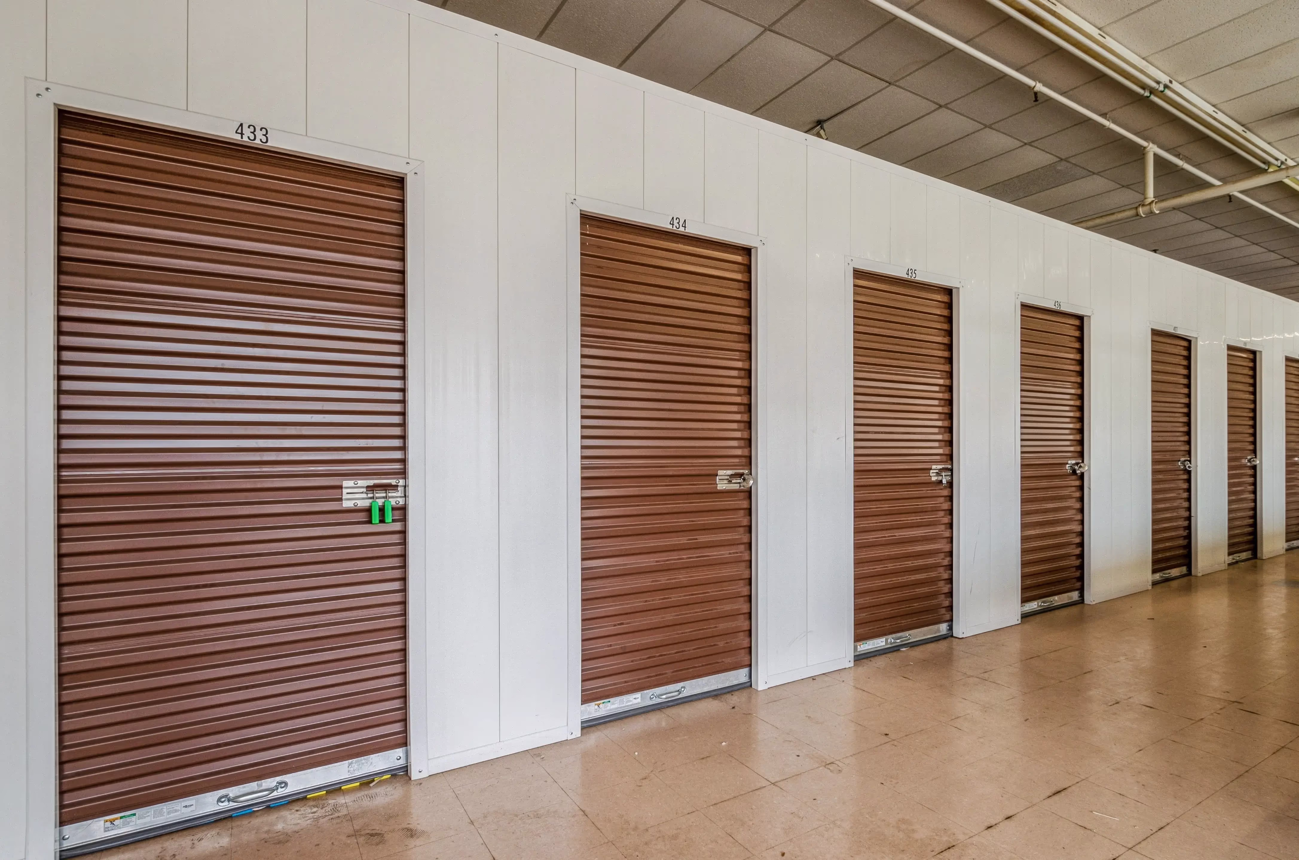 Long interior corridor with brown roll up storage doors and overhead lighting in our Peru IN storage building