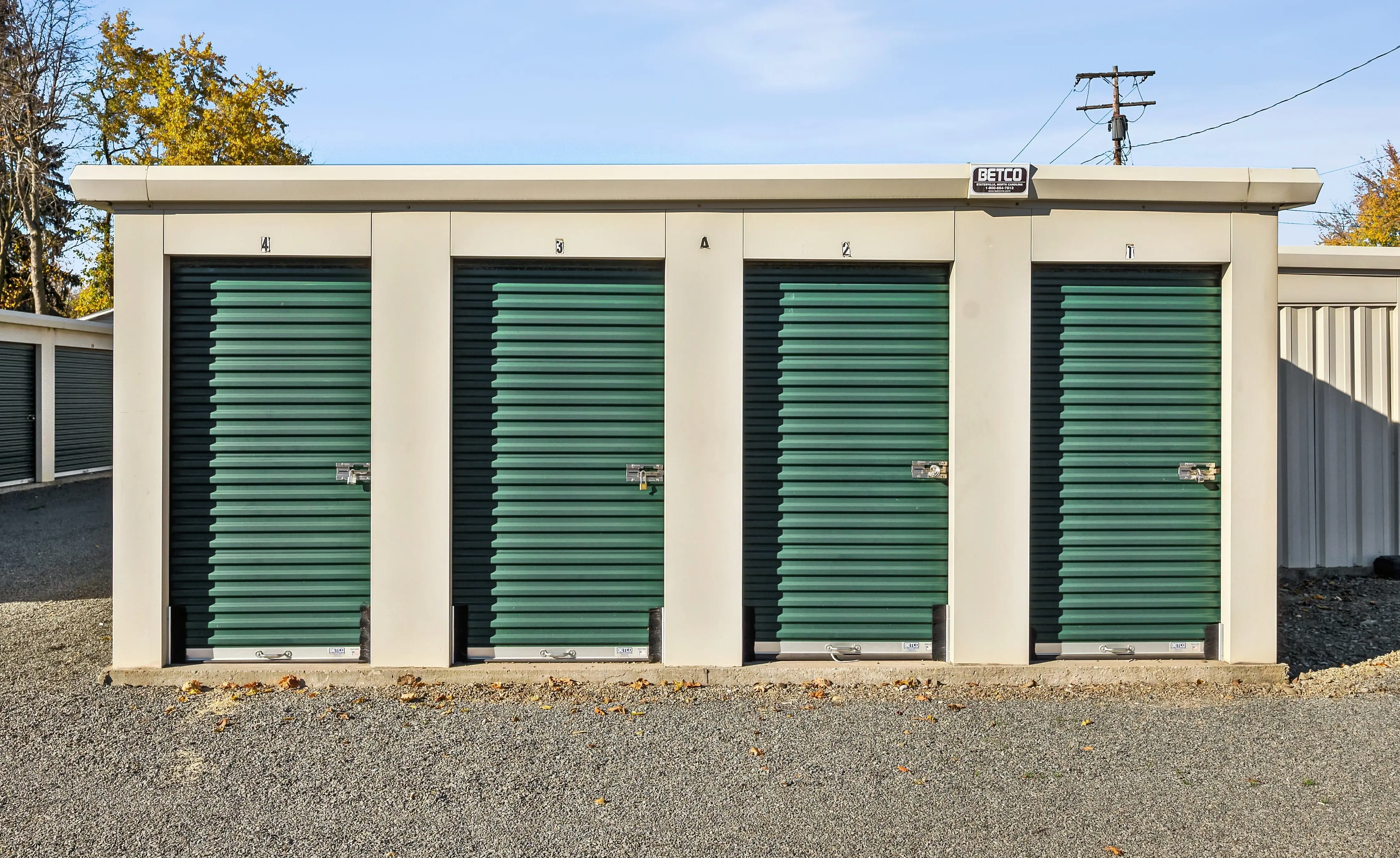 Row of drive up storage units with green roll up doors in Elmira NY