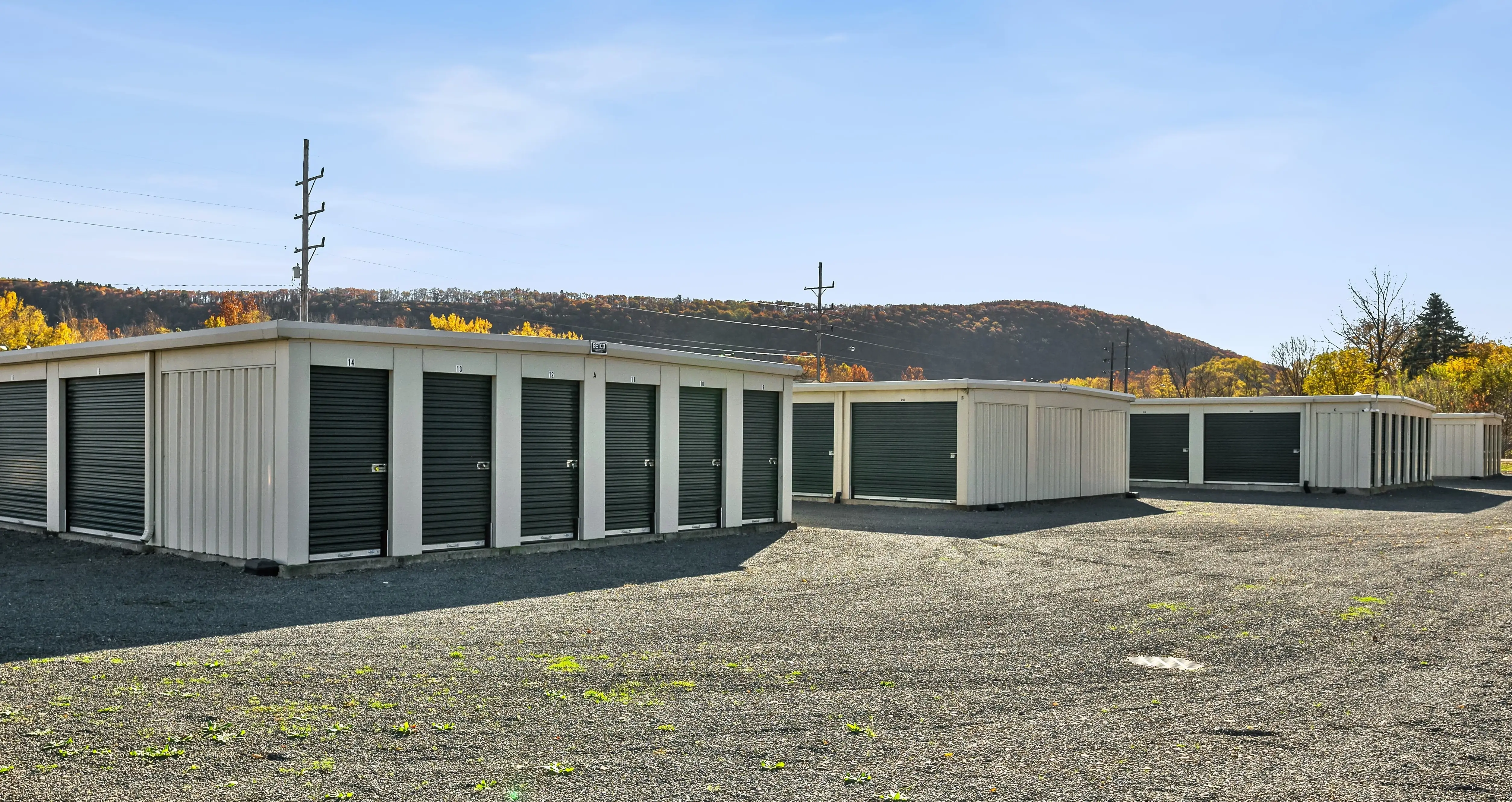 Drive up storage buildings with green doors and gravel access lanes at our Elmira NY facility