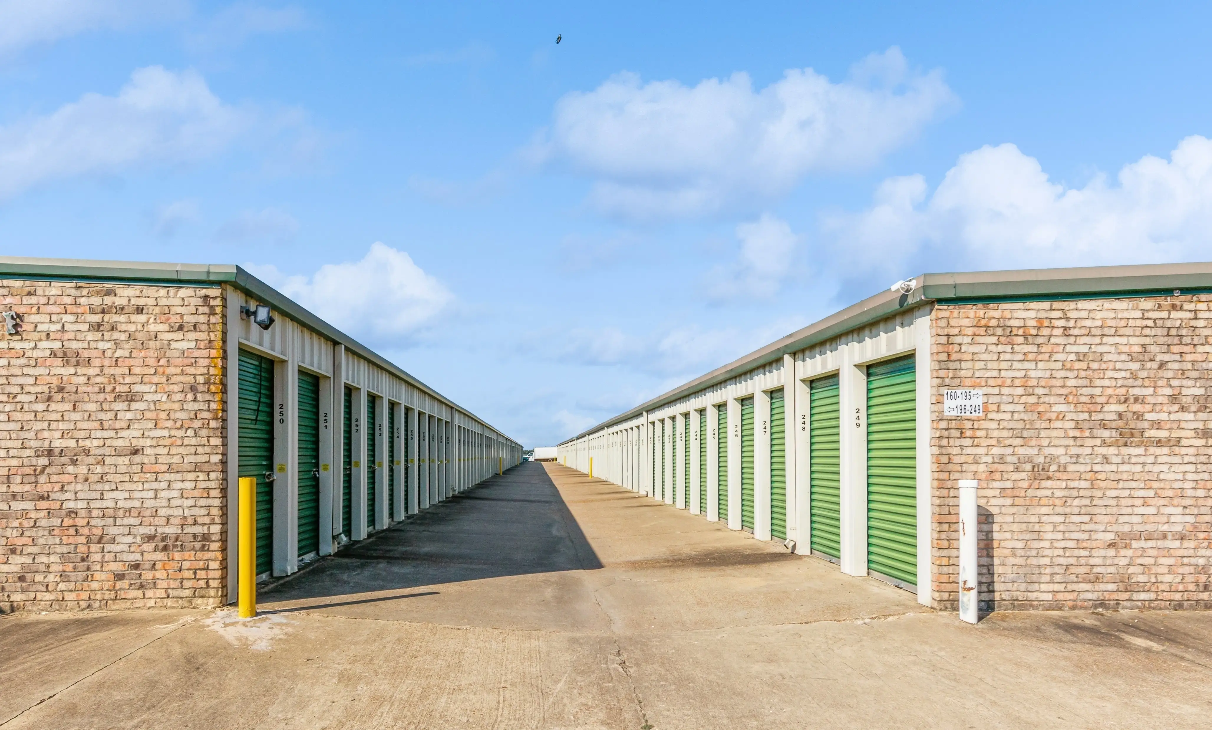 Angled view of brick drive up storage buildings with green roll up doors in Robinsonville MS