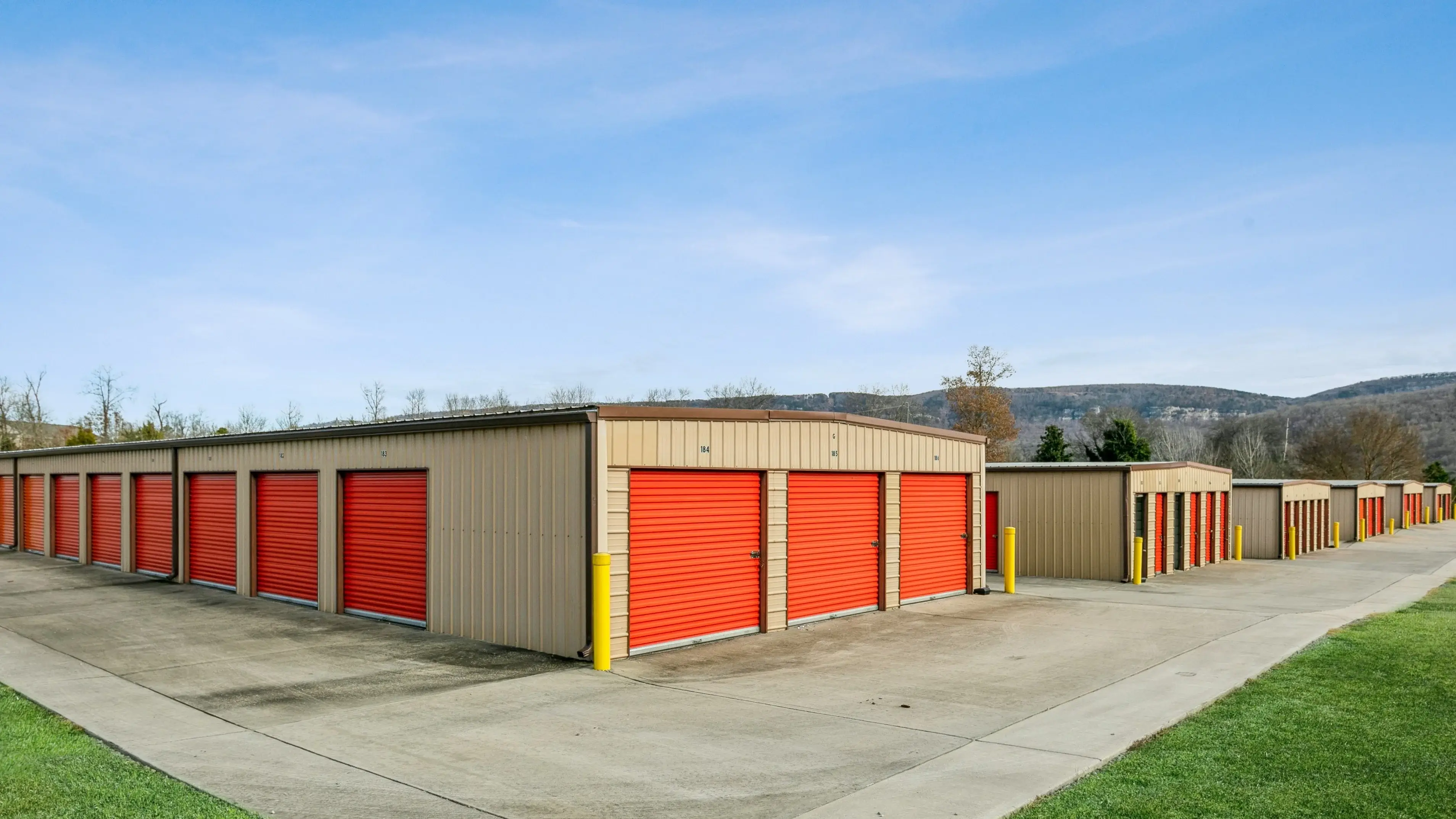 Storage buildings with red roll up doors and grassy edges set against the foothills in Trenton GA
