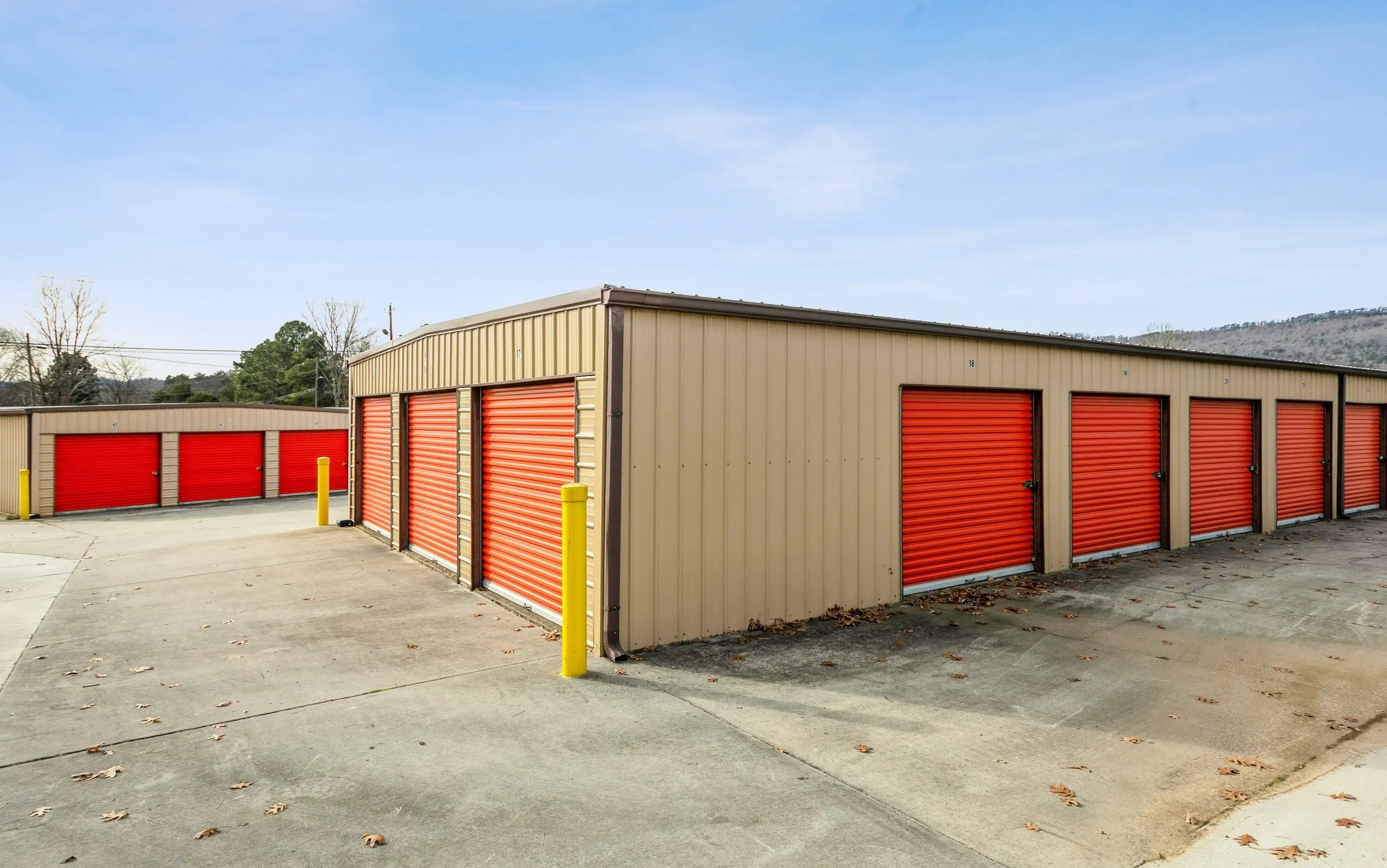 Angled view of tan and red drive up storage units along a gravel lot with mountains visible in the distance in Trenton GA