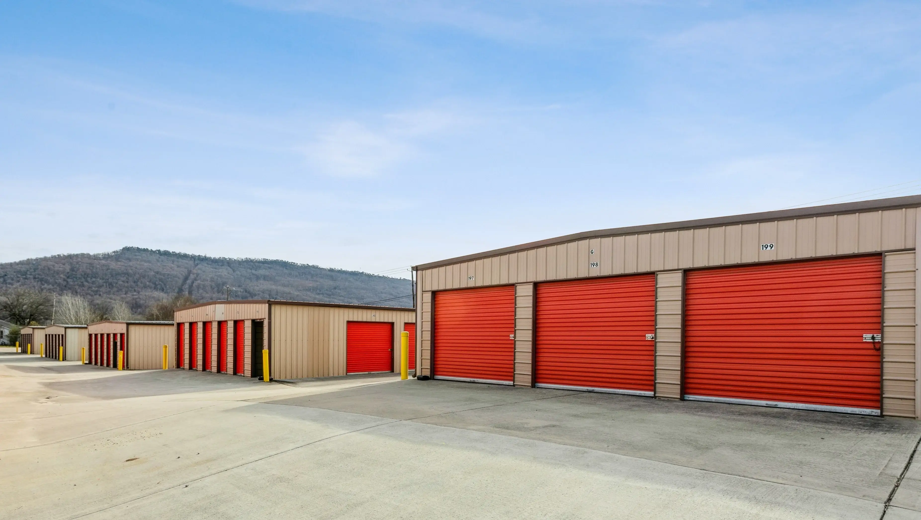 Front view of red roll up storage doors arranged around a smooth paved driveway in Trenton GA