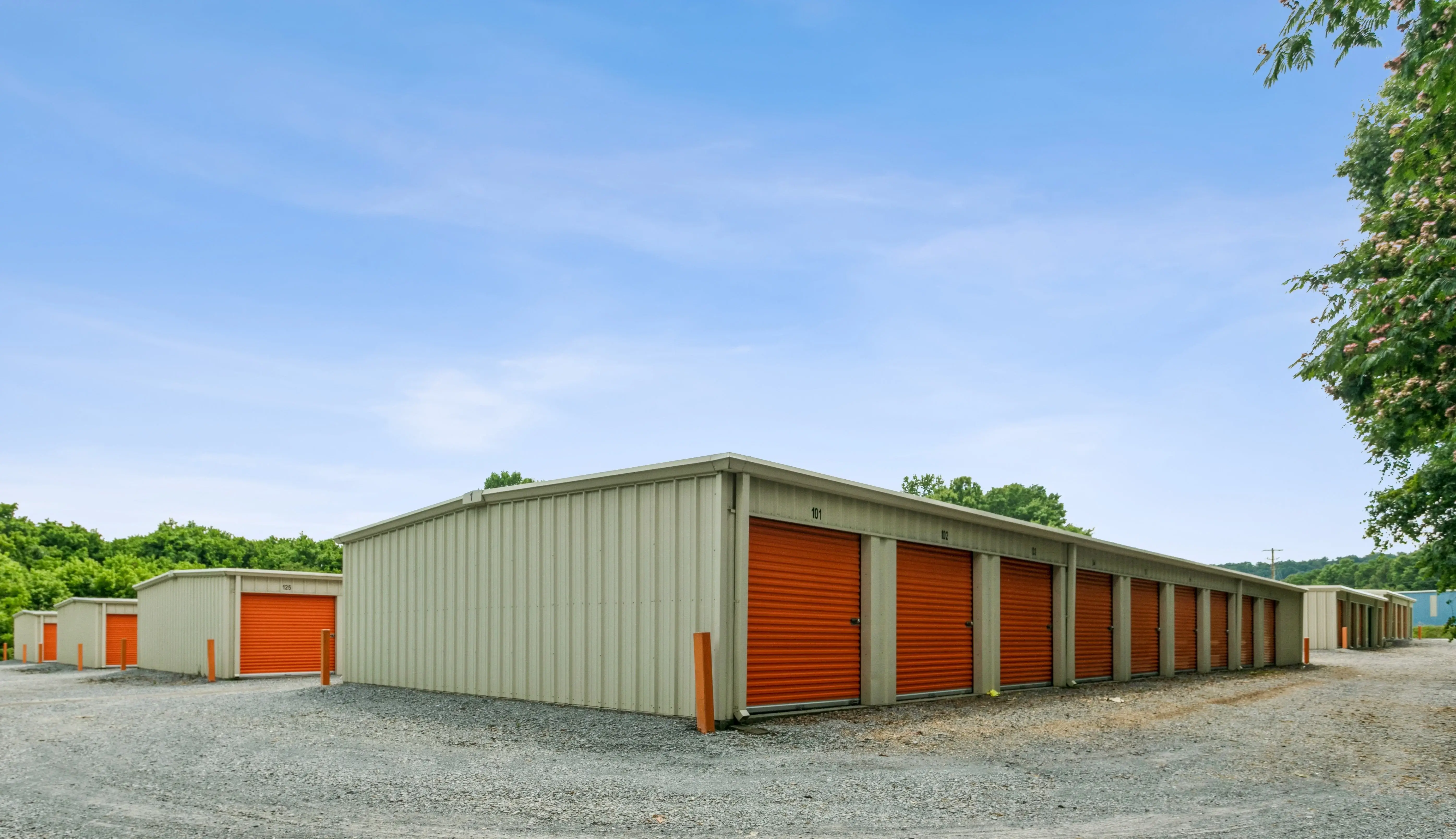 Several rows of orange roll up storage units positioned on a gently sloped gravel lot in Trion GA