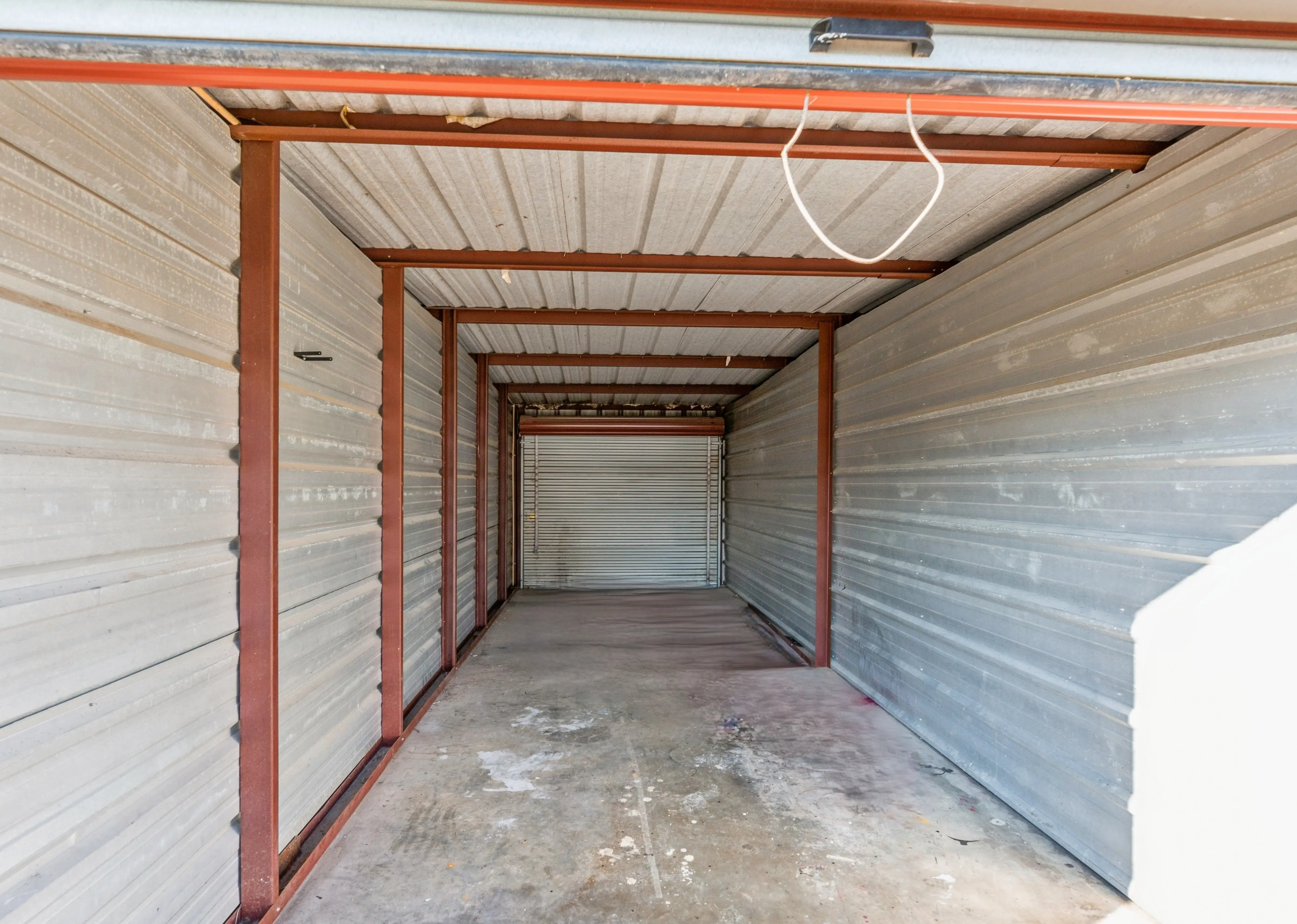 Interior of an empty storage unit in Walls MS showing metal walls and concrete flooring