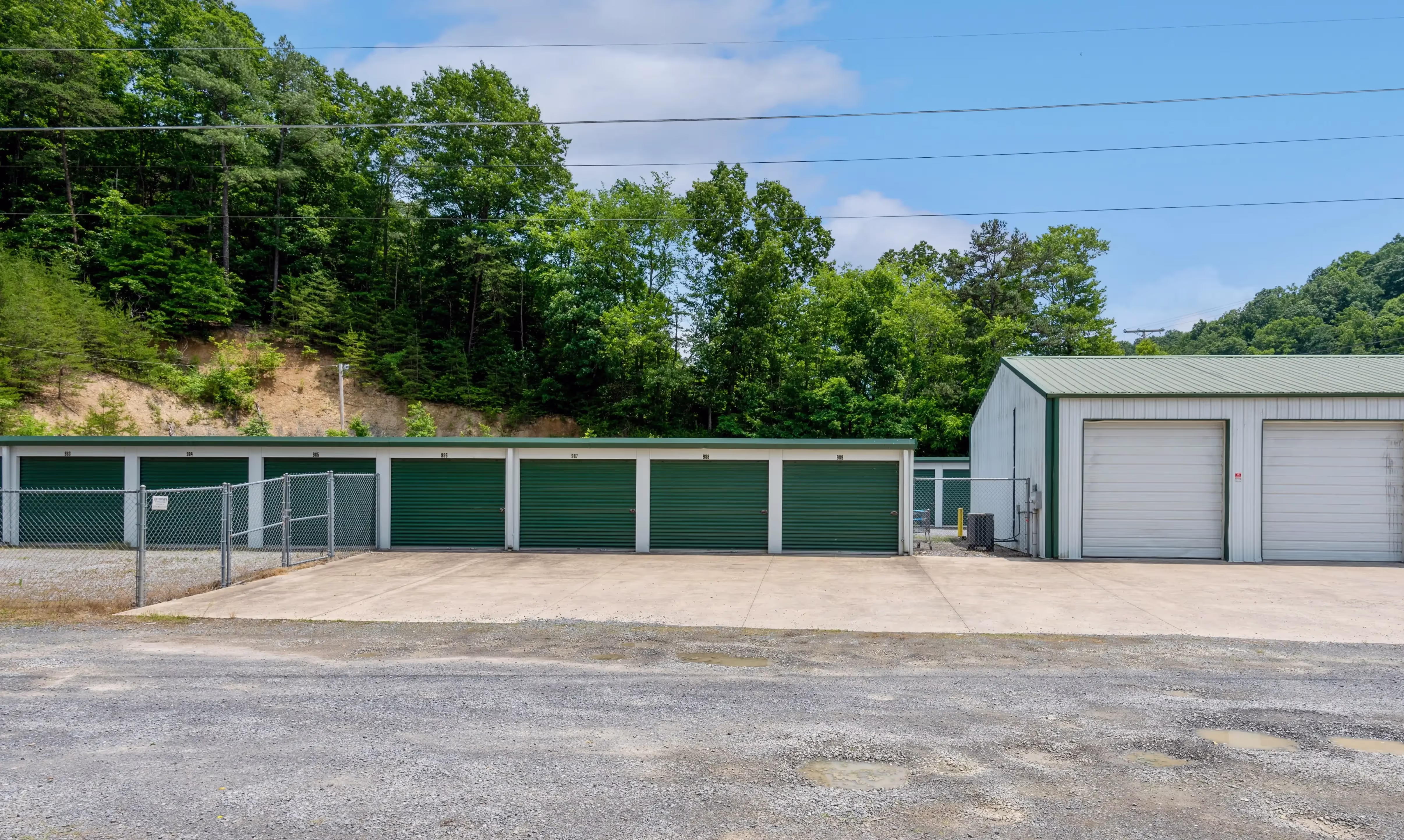 Drive up storage buildings with green roll up doors and gravel access lanes in Abingdon VA