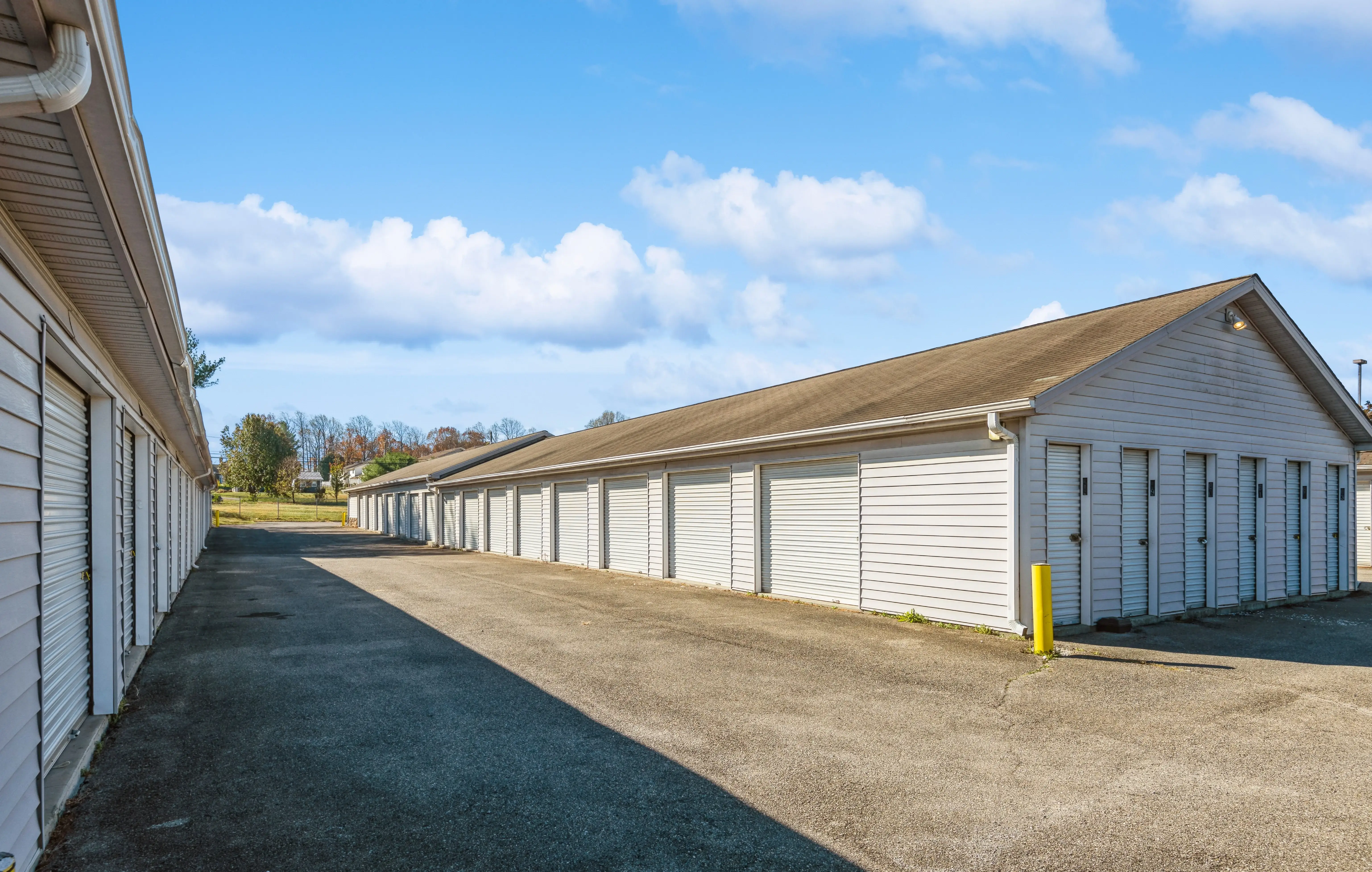 Row of drive up storage units with white roll up doors along paved access lane in Christiansburg VA