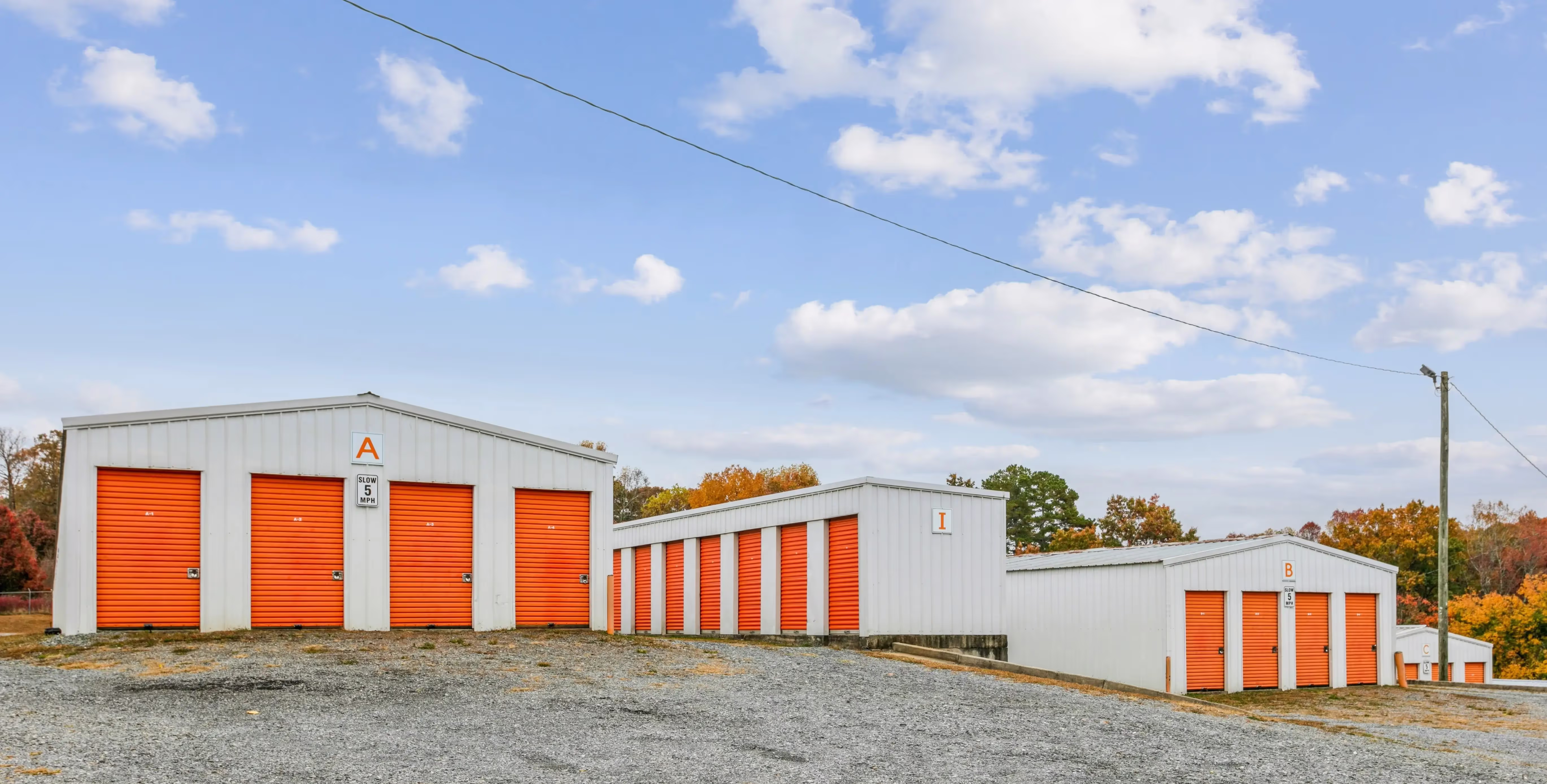 Wide exterior view of drive up storage units with orange doors at our Ellijay GA location