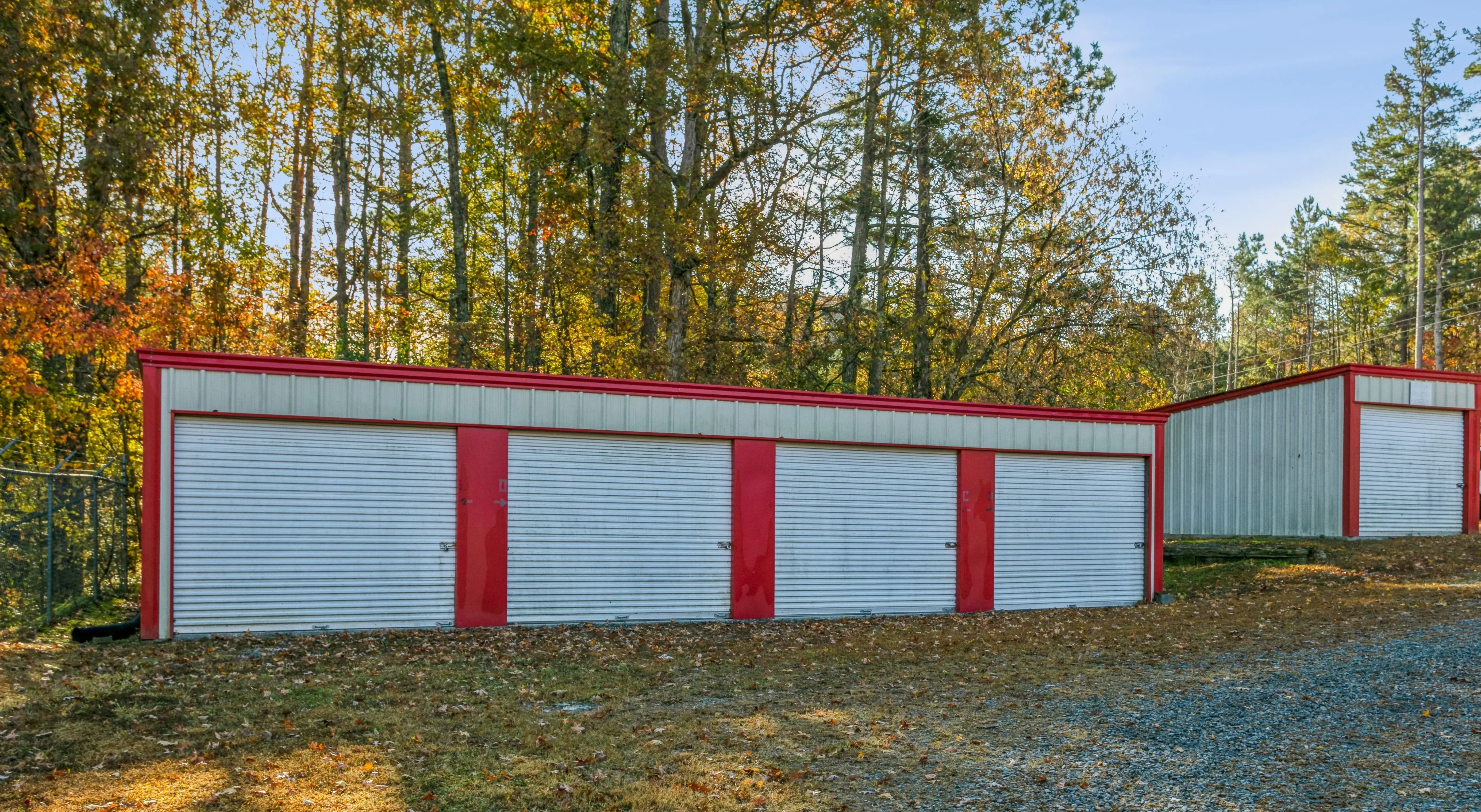 Exterior view of storage buildings with white roll up doors and red trim in Ellijay GA