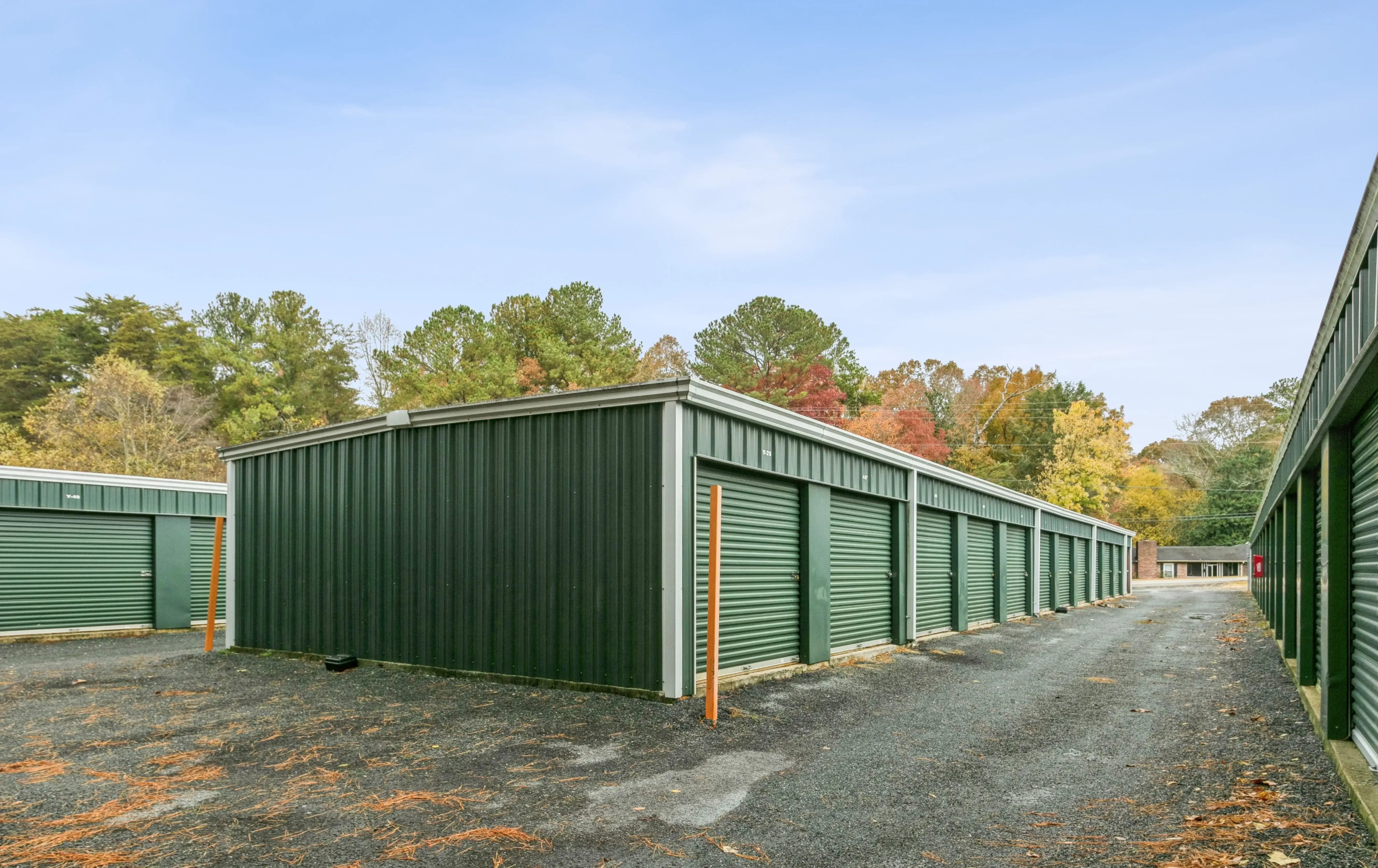 Long alleyway between storage buildings with green doors and a compact gravel surface at our Ellijay GA facility