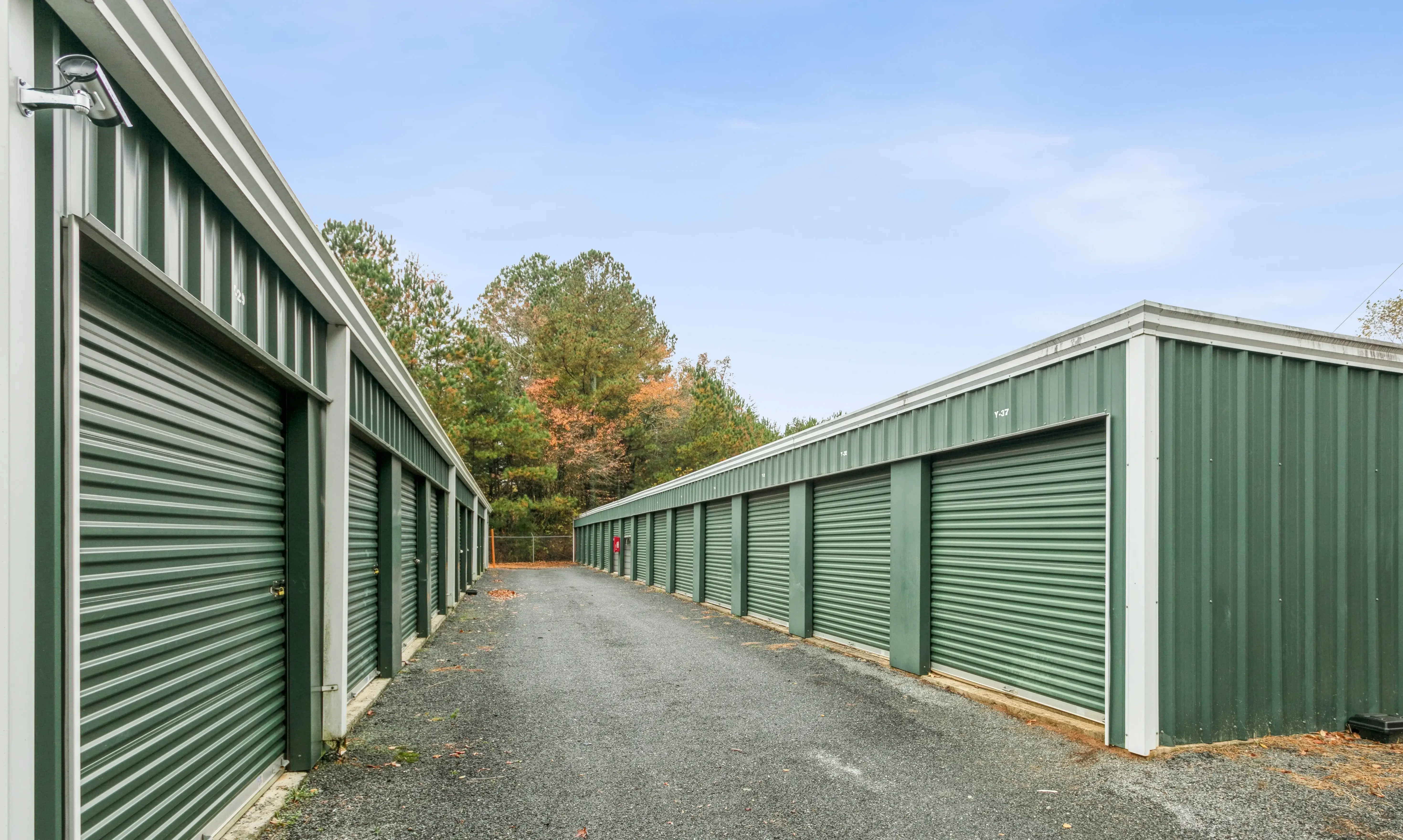 Row of storage units running uphill on a gravel drive, surrounded by trees at our Ellijay GA facility