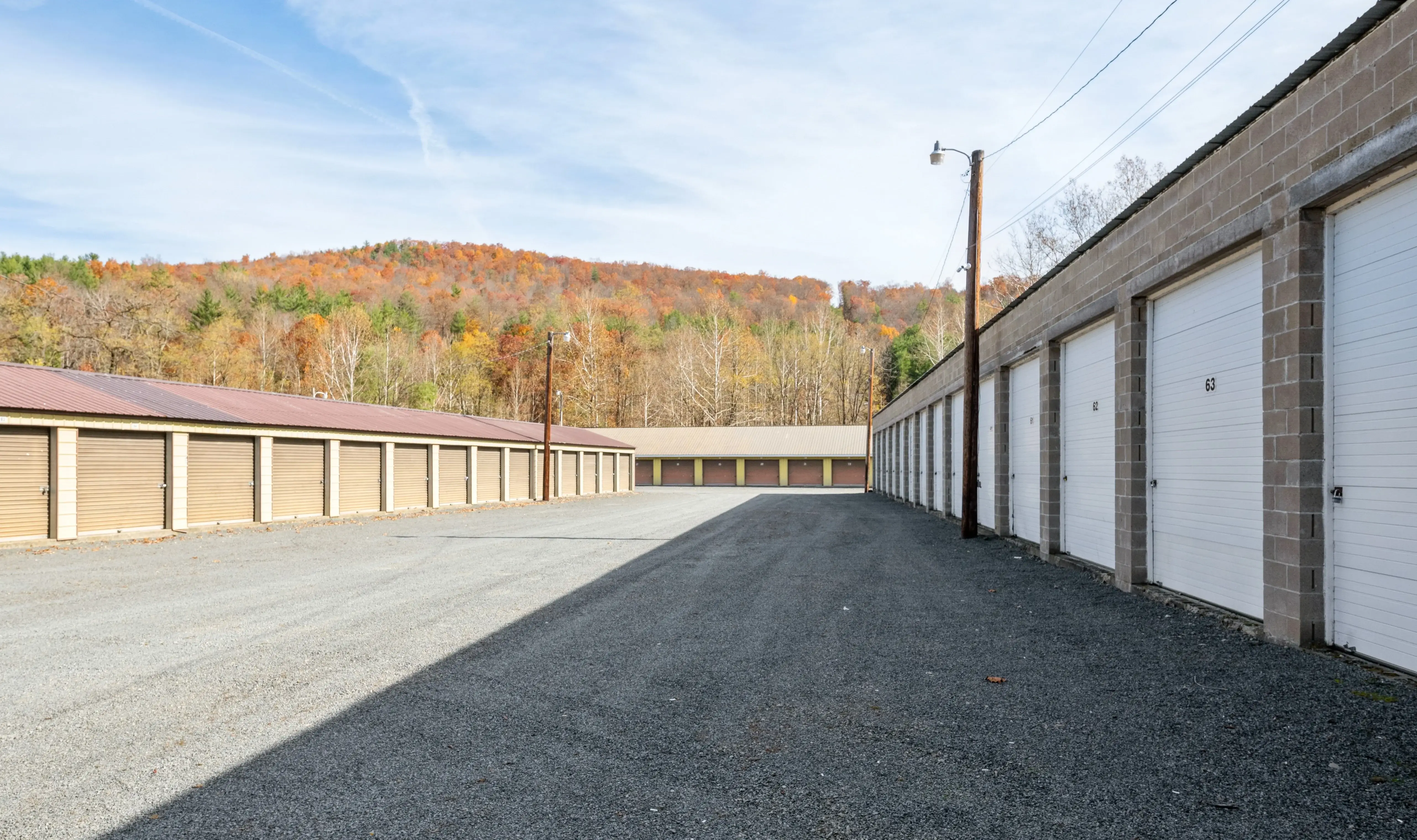 Drive up storage units with white roll up doors and gravel access lanes in Gillett PA