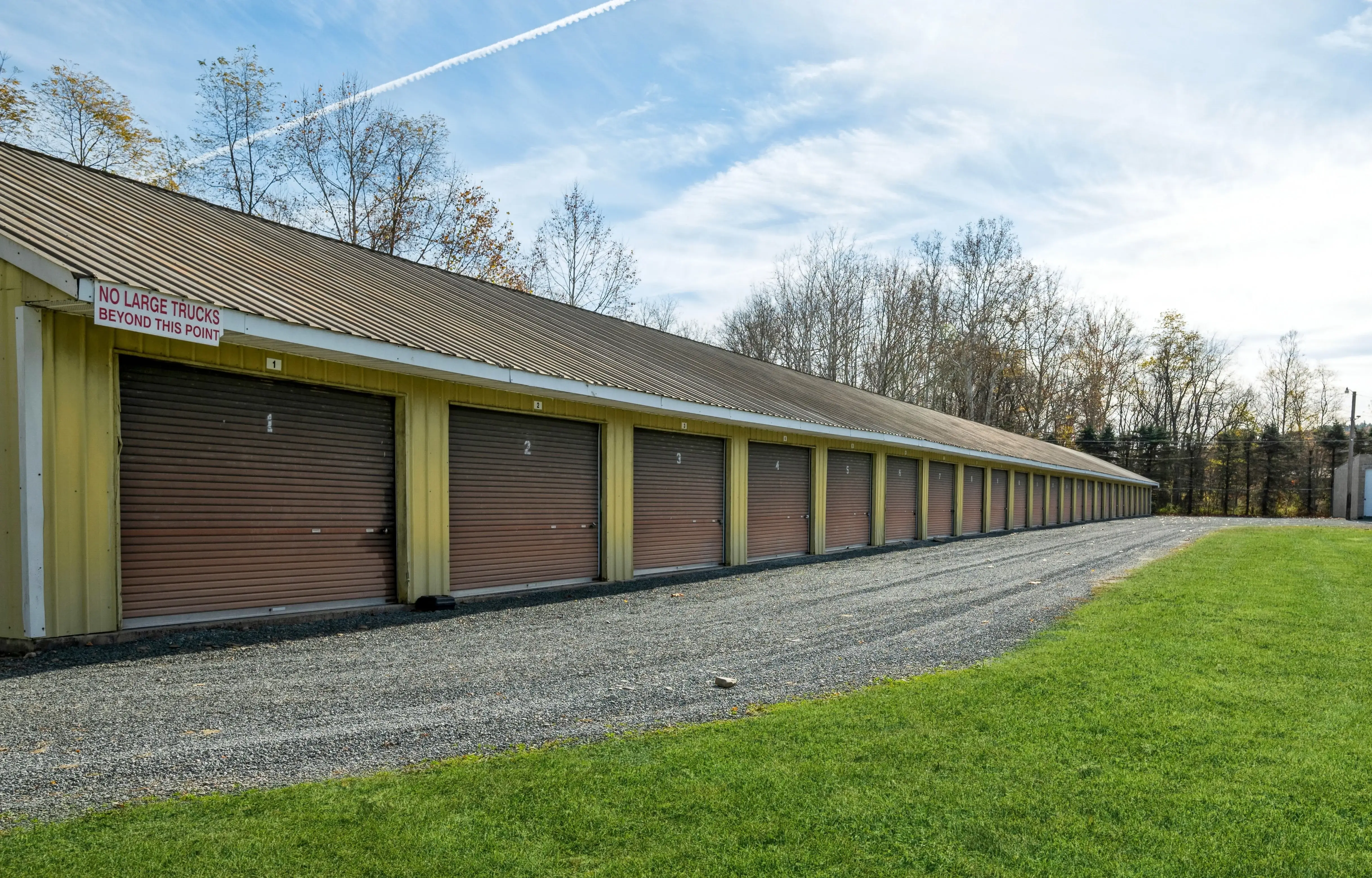Exterior row of storage units with white roll up doors and gravel driveway in Gillett PA