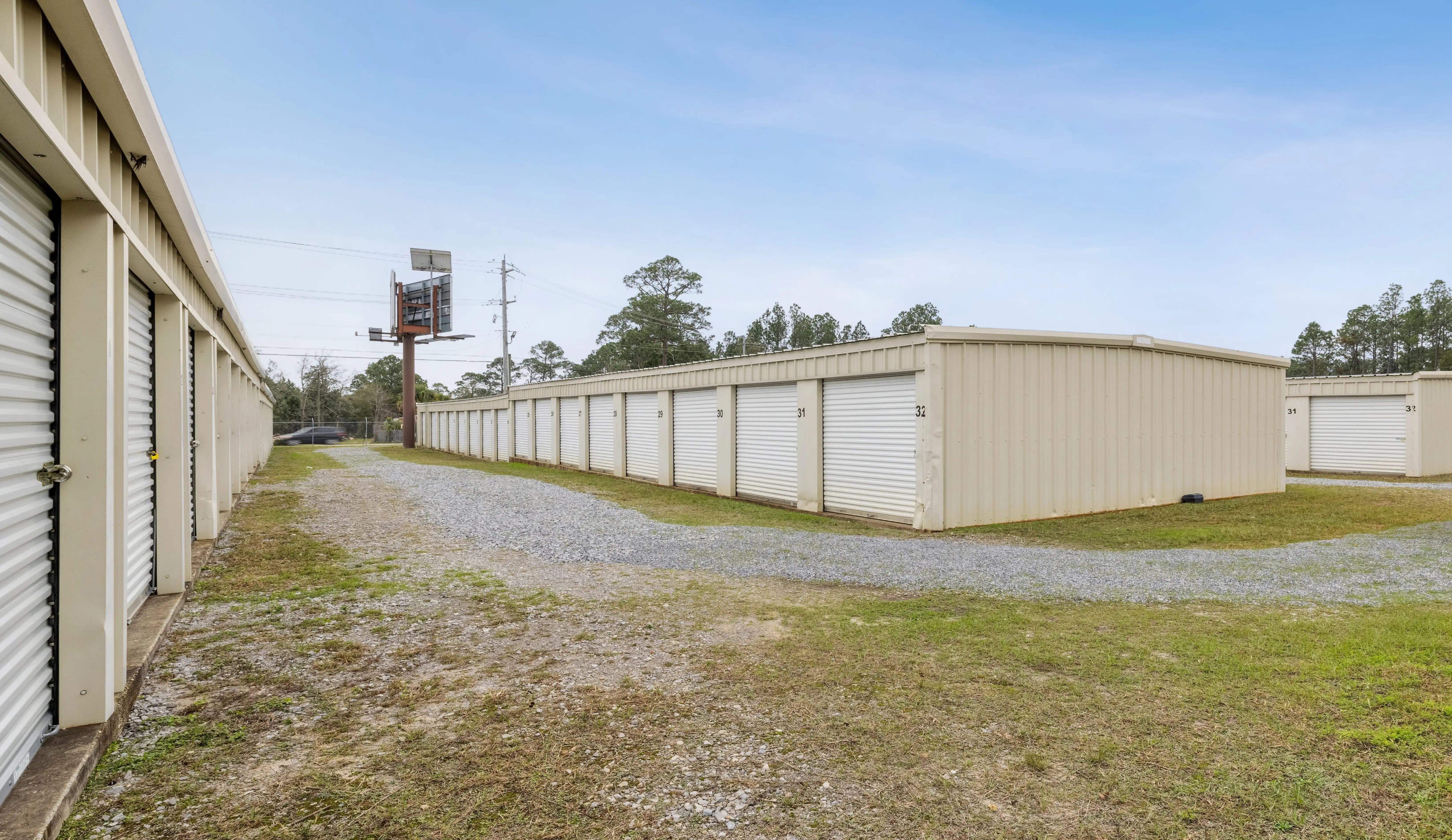 Angled row of white roll up storage units positioned along a gravel driveway at our Pensacola FL facility