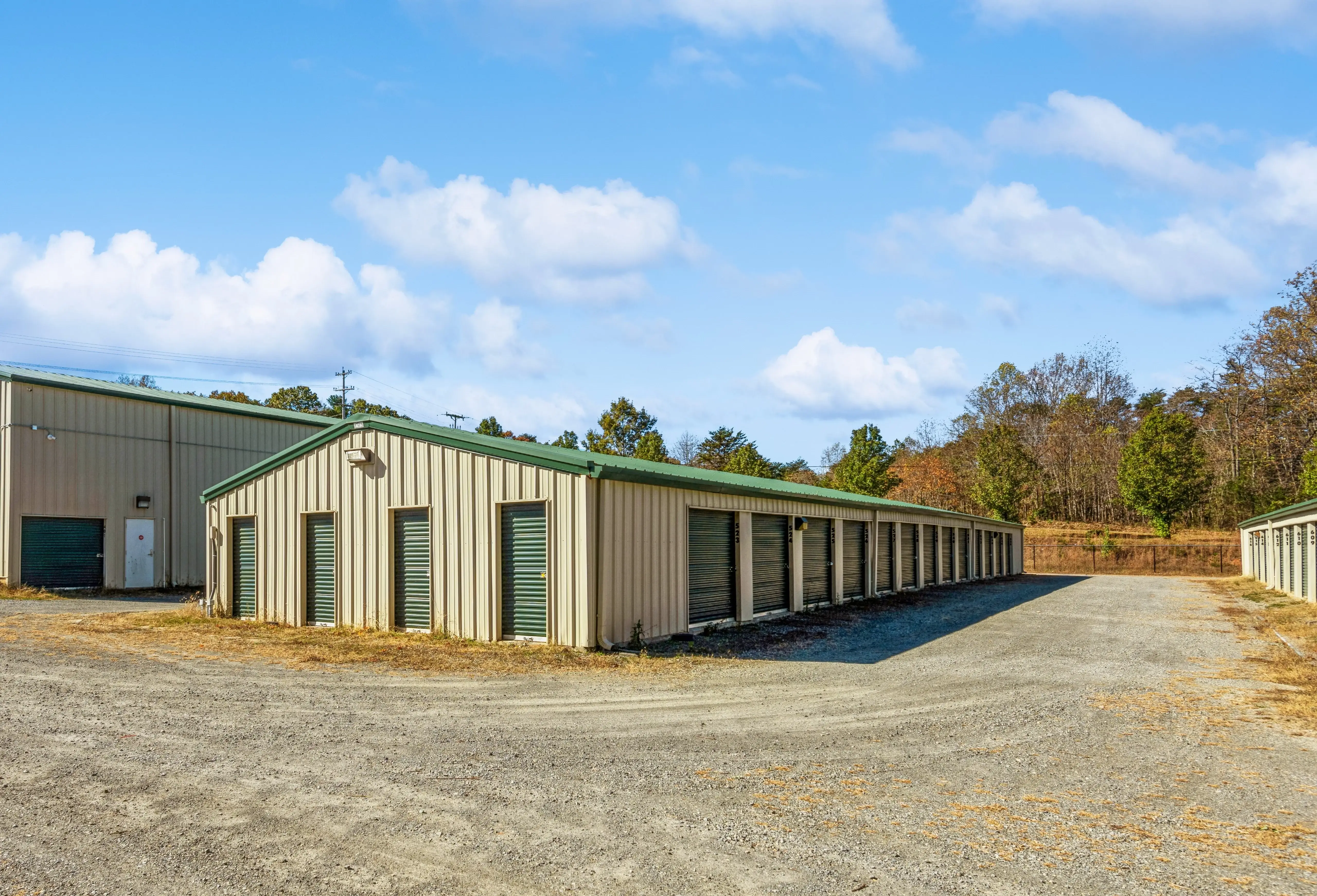 Exterior view of drive up storage units with green roll up doors on gravel driveway in Moneta VA