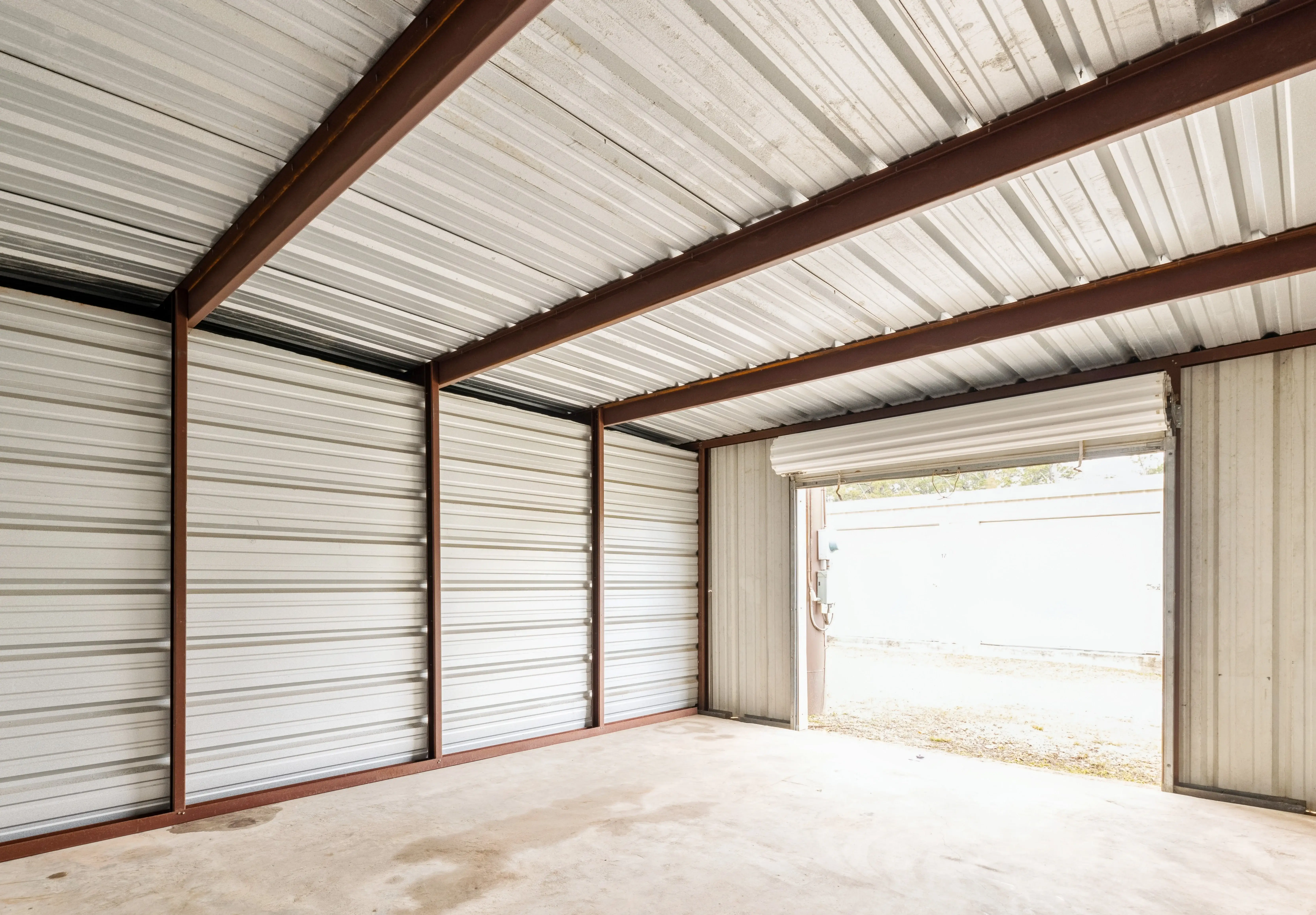 Interior view of a large empty storage unit with steel framing and bright natural light entering through the open door in Pensacola FL