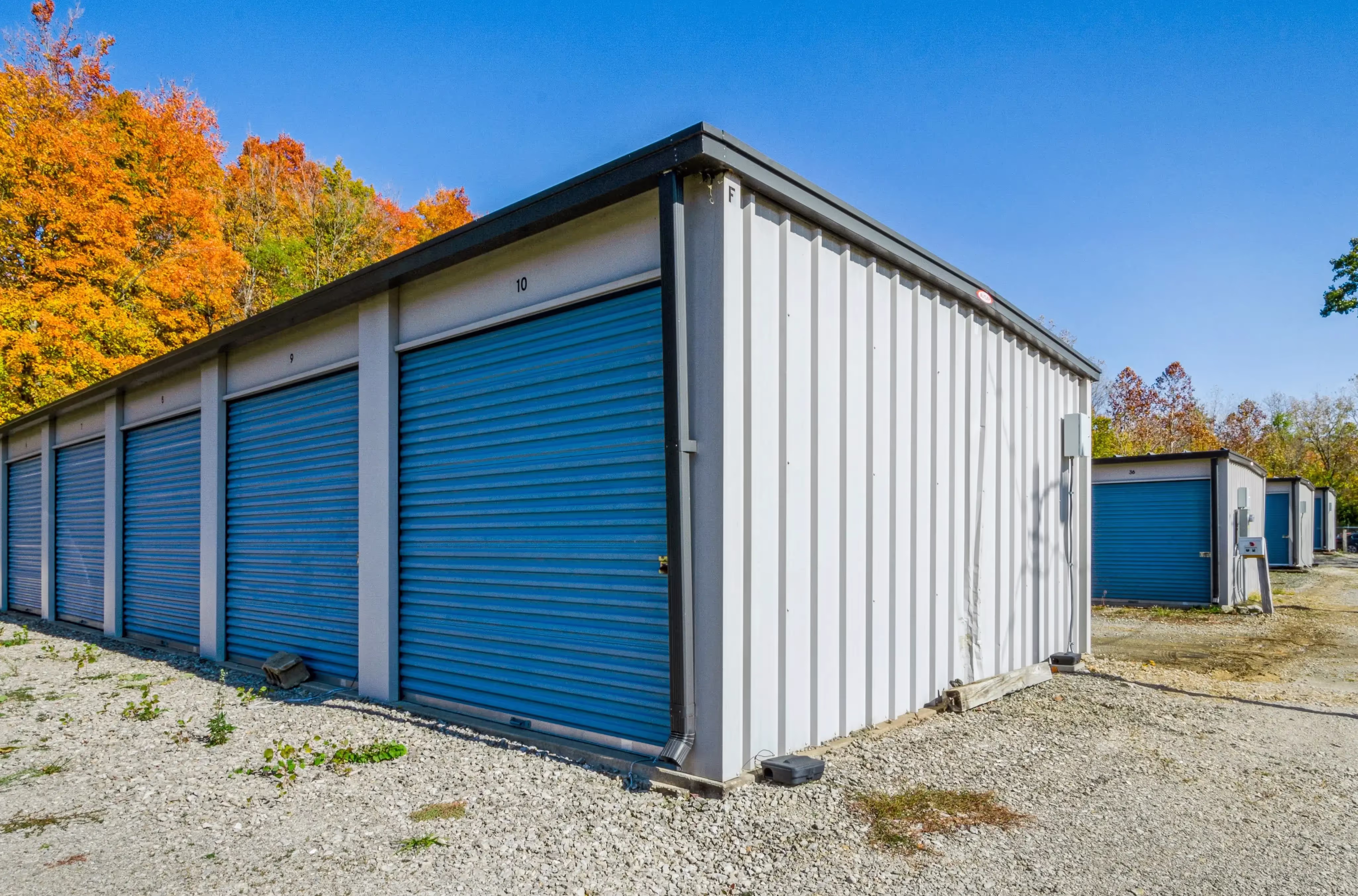 Angled shot of a storage building showing a blue roll up door and sloped gravel surface in Peru IN