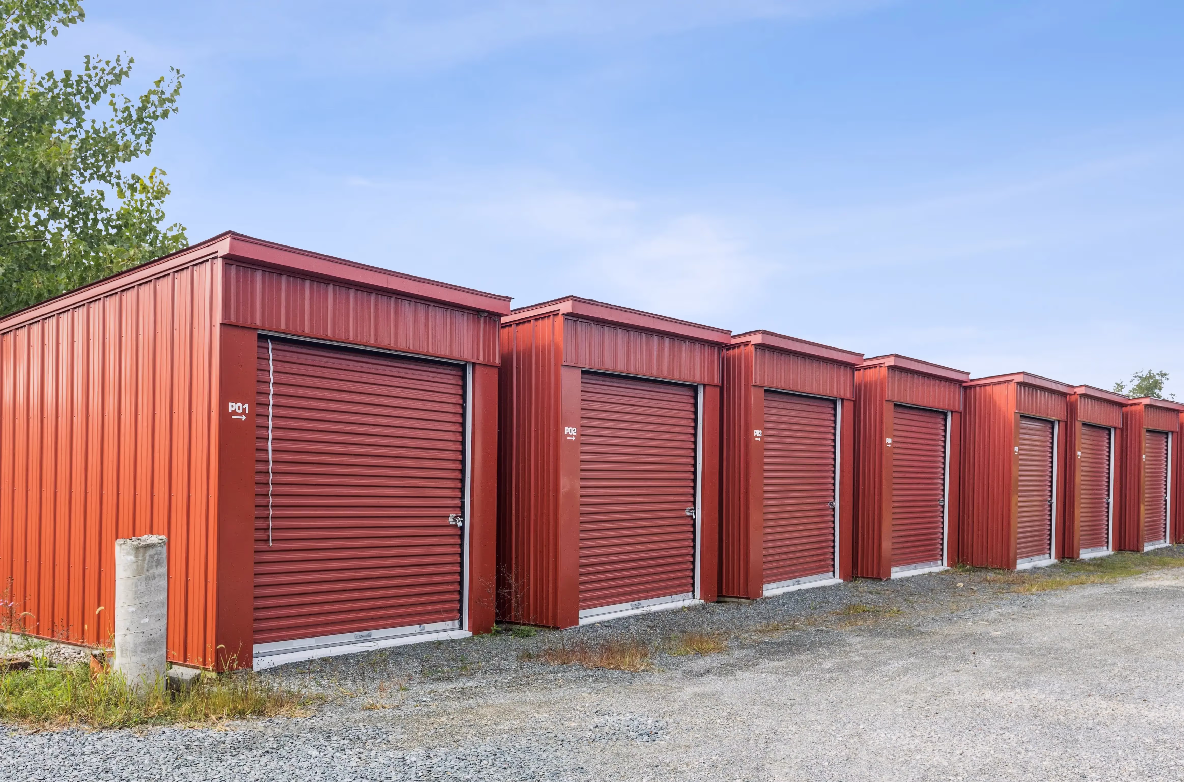 Angled exterior view of drive up storage buildings with red roll up doors in Troy NY