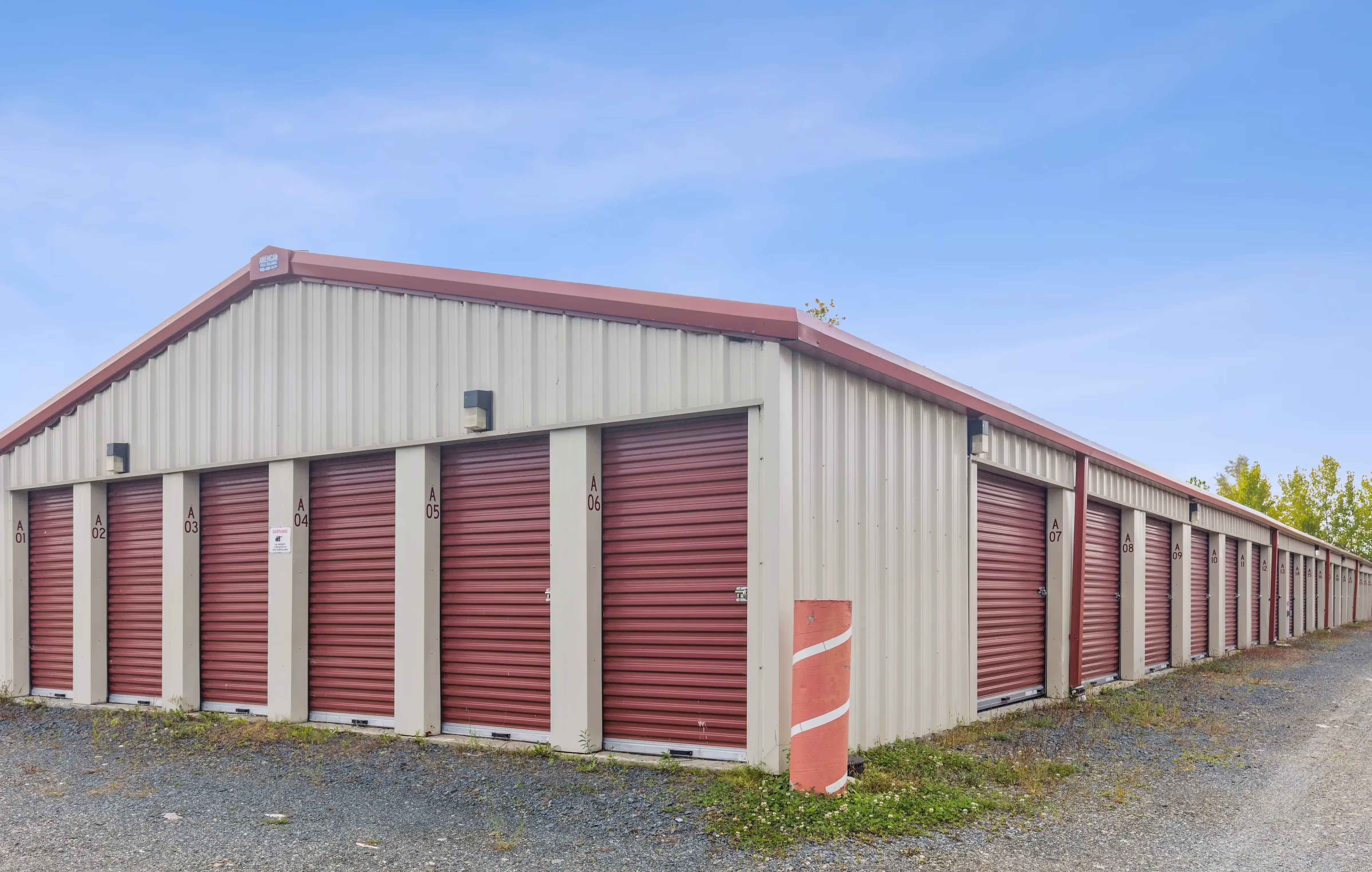 Angled view of storage buildings with red roll up doors and paved entry area at our Troy NY facility
