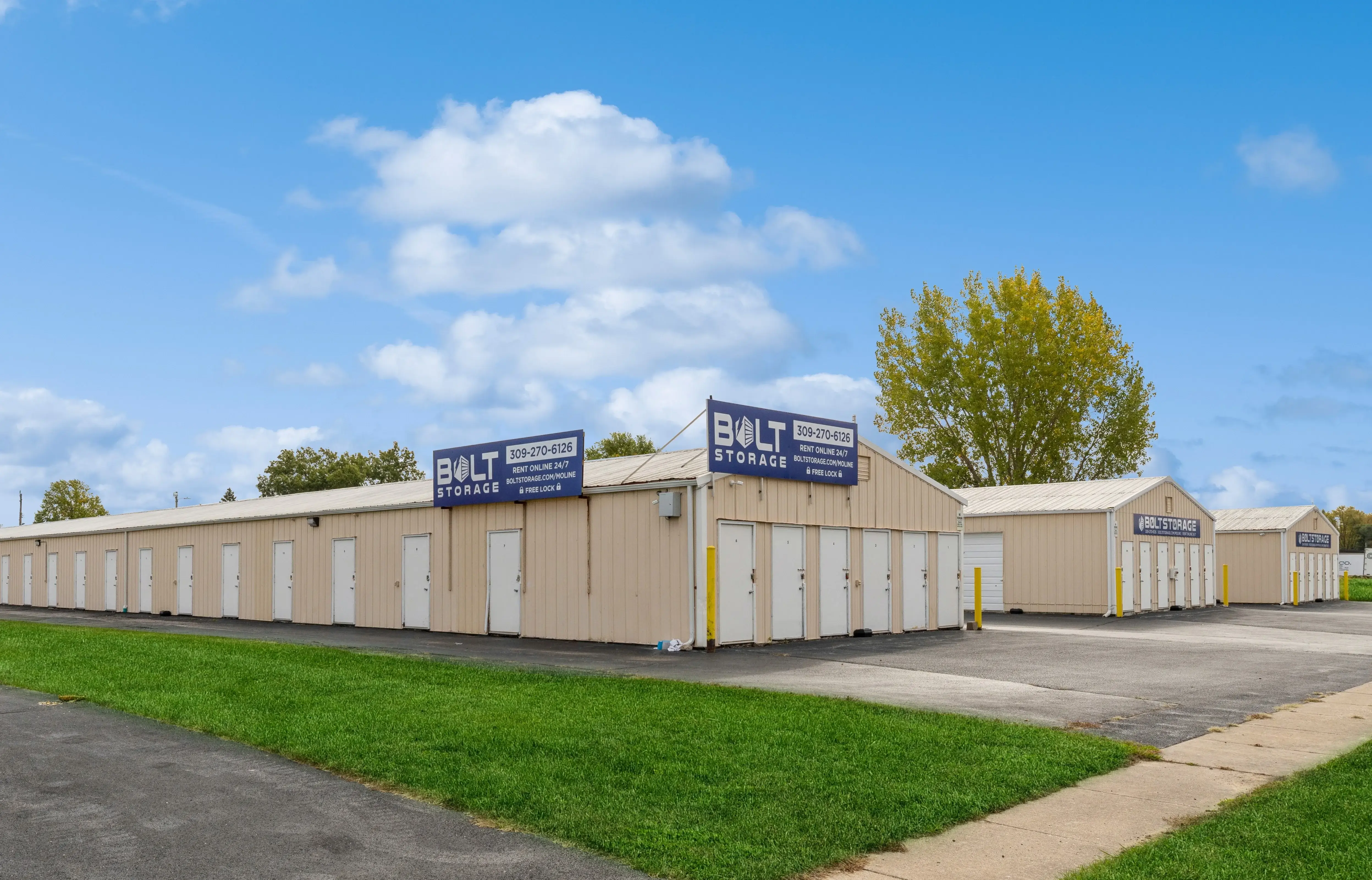 Exterior view of drive up storage buildings with white roll up doors along paved driveway in Moline IL