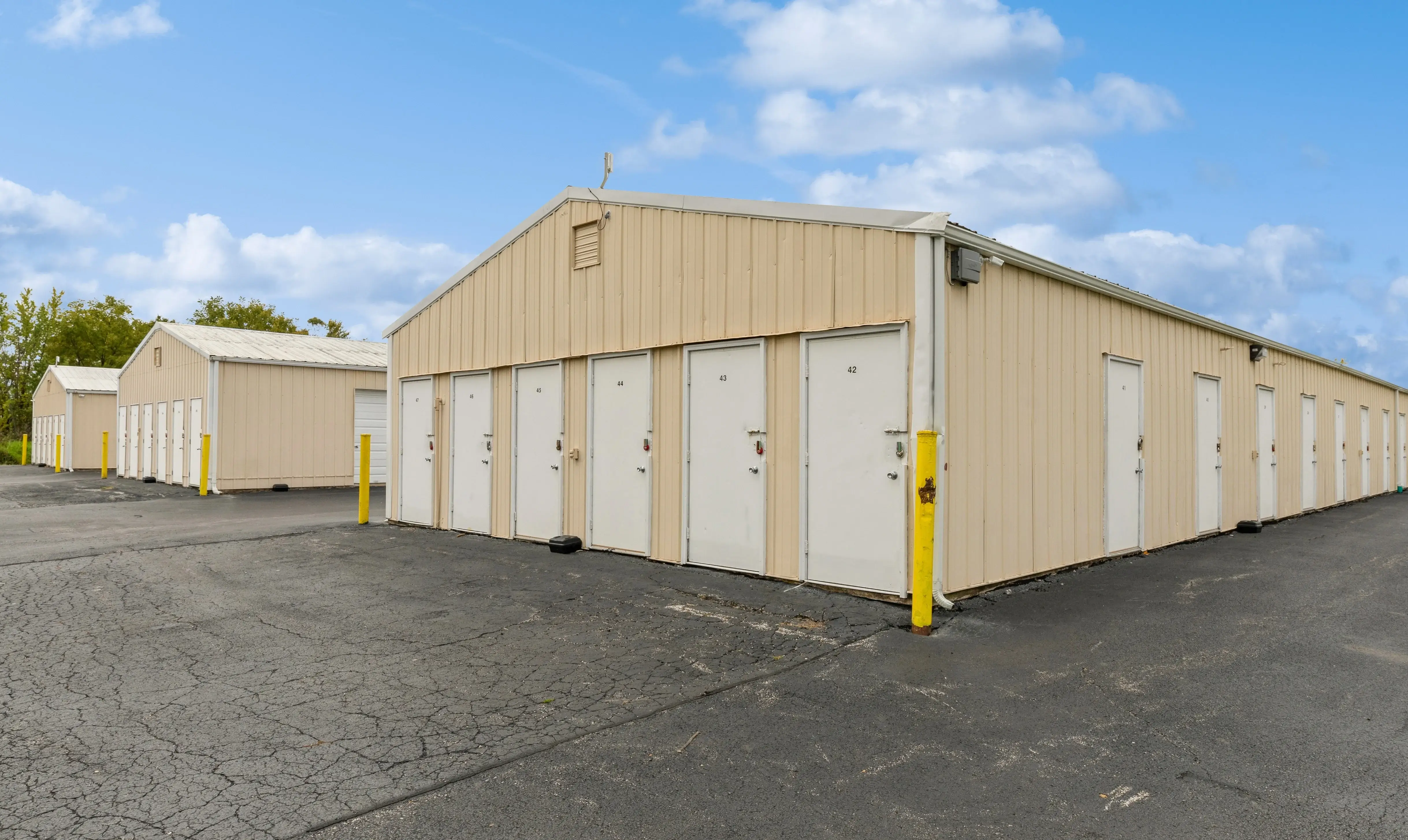 Row of drive up storage units with white roll up doors along paved driveway in Moline IL
