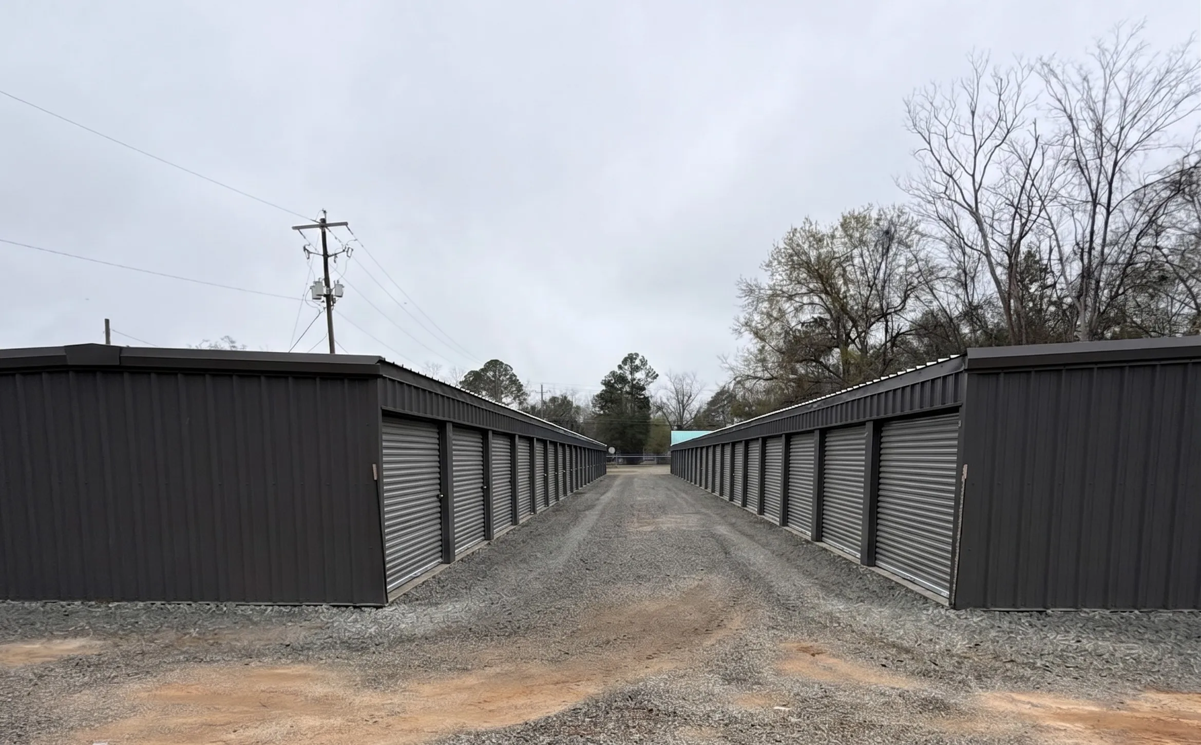 Front view of two separate self storage buildings at the Baxley, GA 31513 facility, with individual units, roll up doors, and large gravel areas for driving trucks and trailers