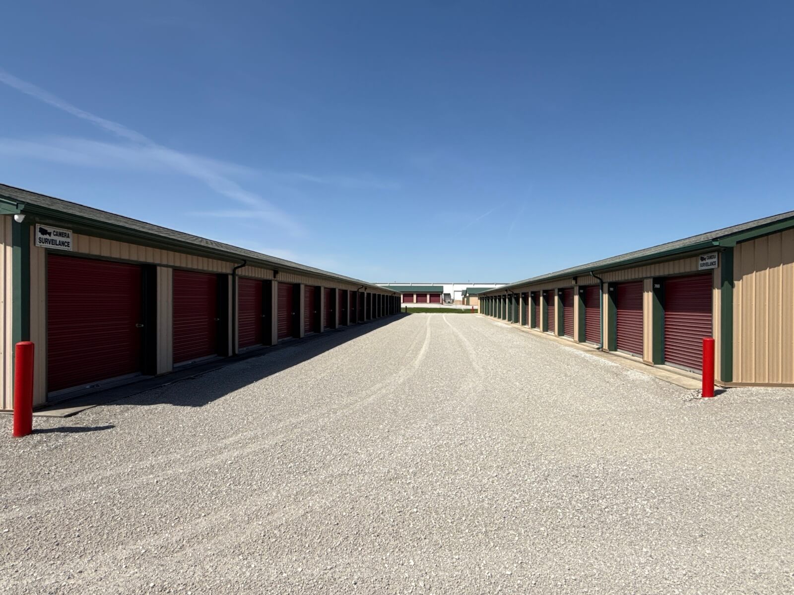 Wide-angle view down a gravel drive between two rows of self storage units at Bolt Storage Ossian, IN