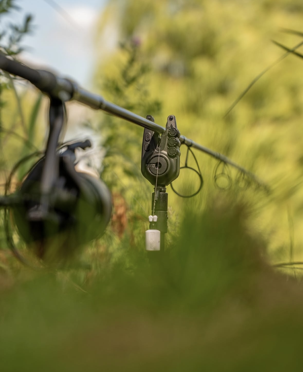 Appareil de détection de touches de canne à pêche placé sur un support dans l'herbe verte.