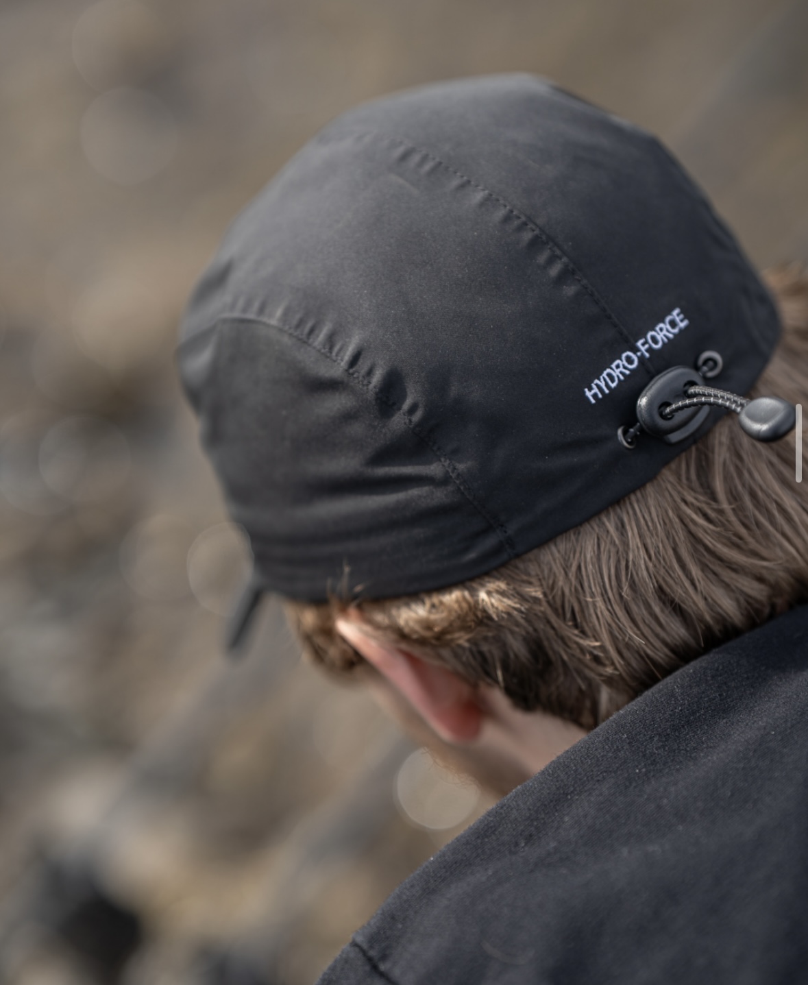 Vue rapprochée de l'arrière d'une personne portant une casquette noire Hydro-Force avec une cordelette de serrage.
