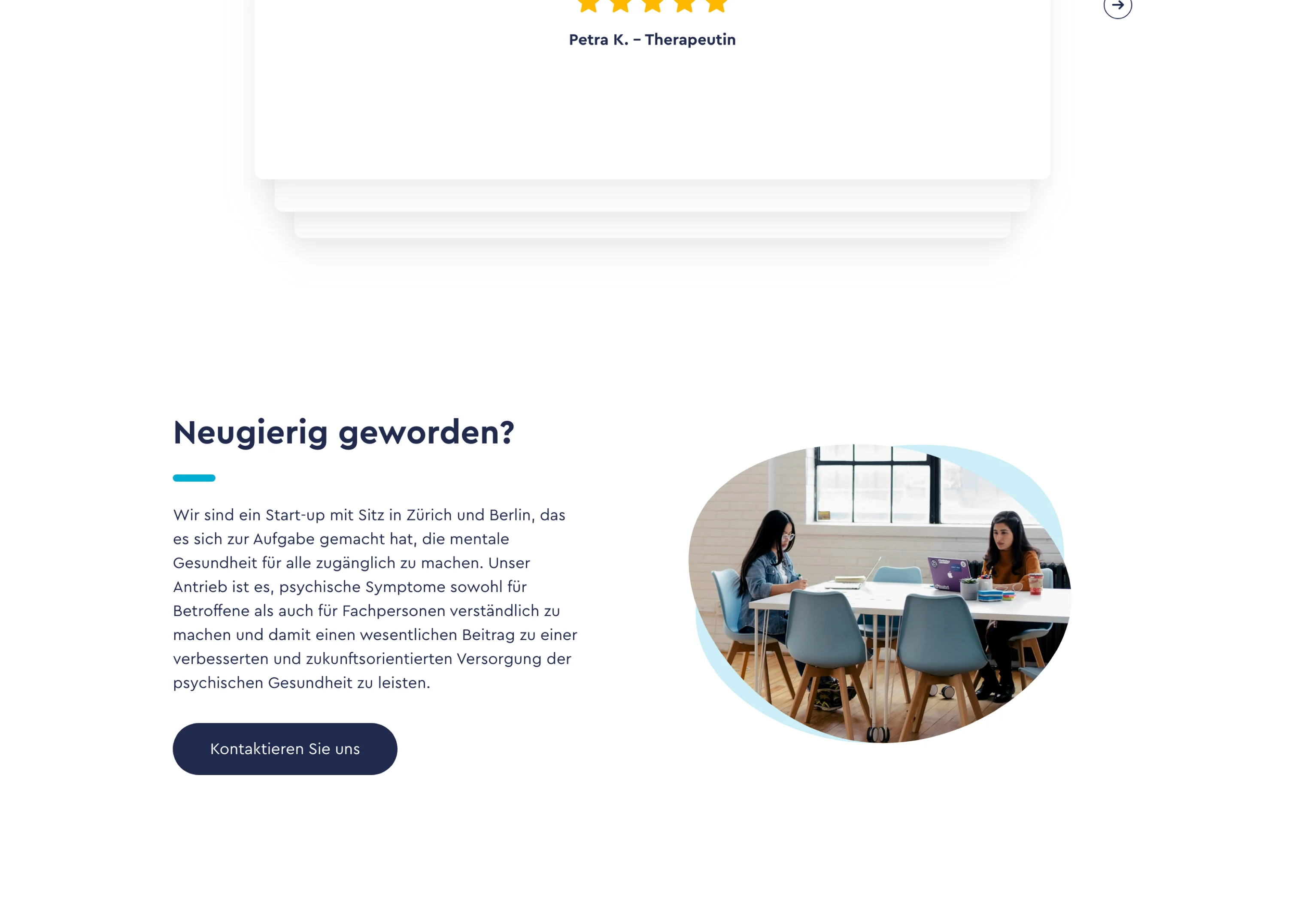 Two women sitting at a table with laptops and drinks in a bright workspace with large windows.