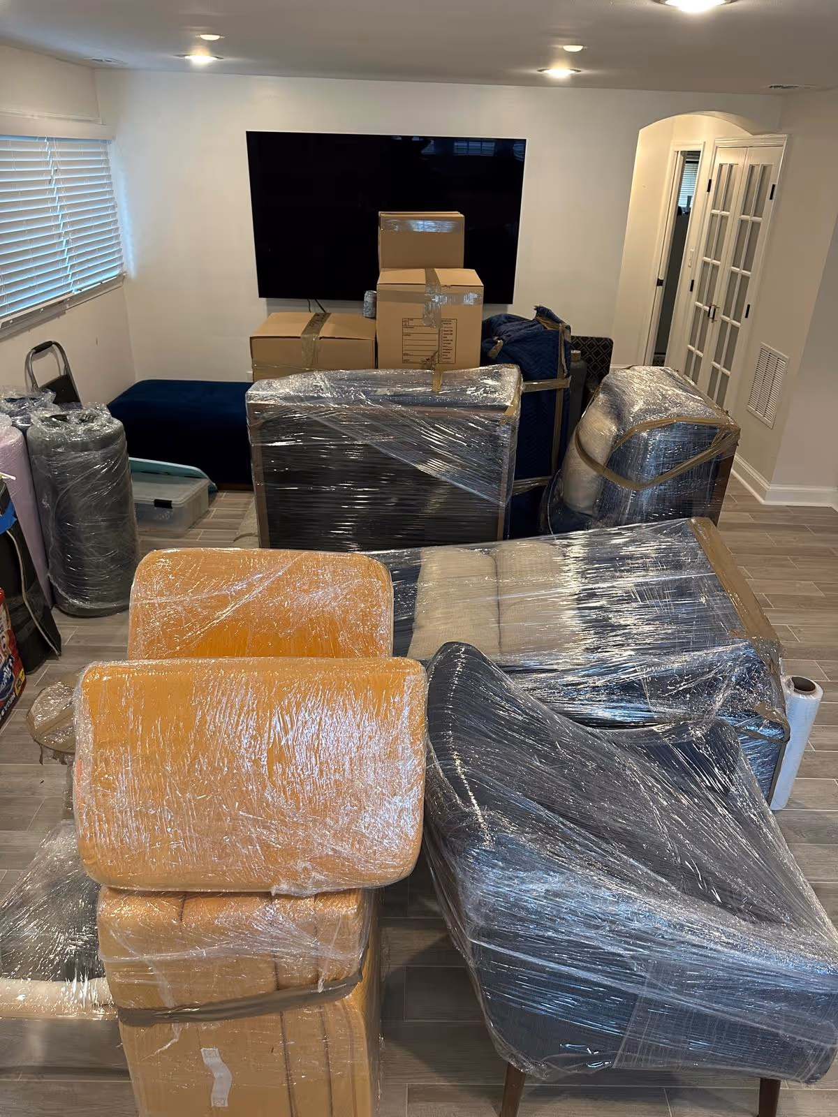 Living room furniture and boxes wrapped in plastic wrap ready for moving or storage.