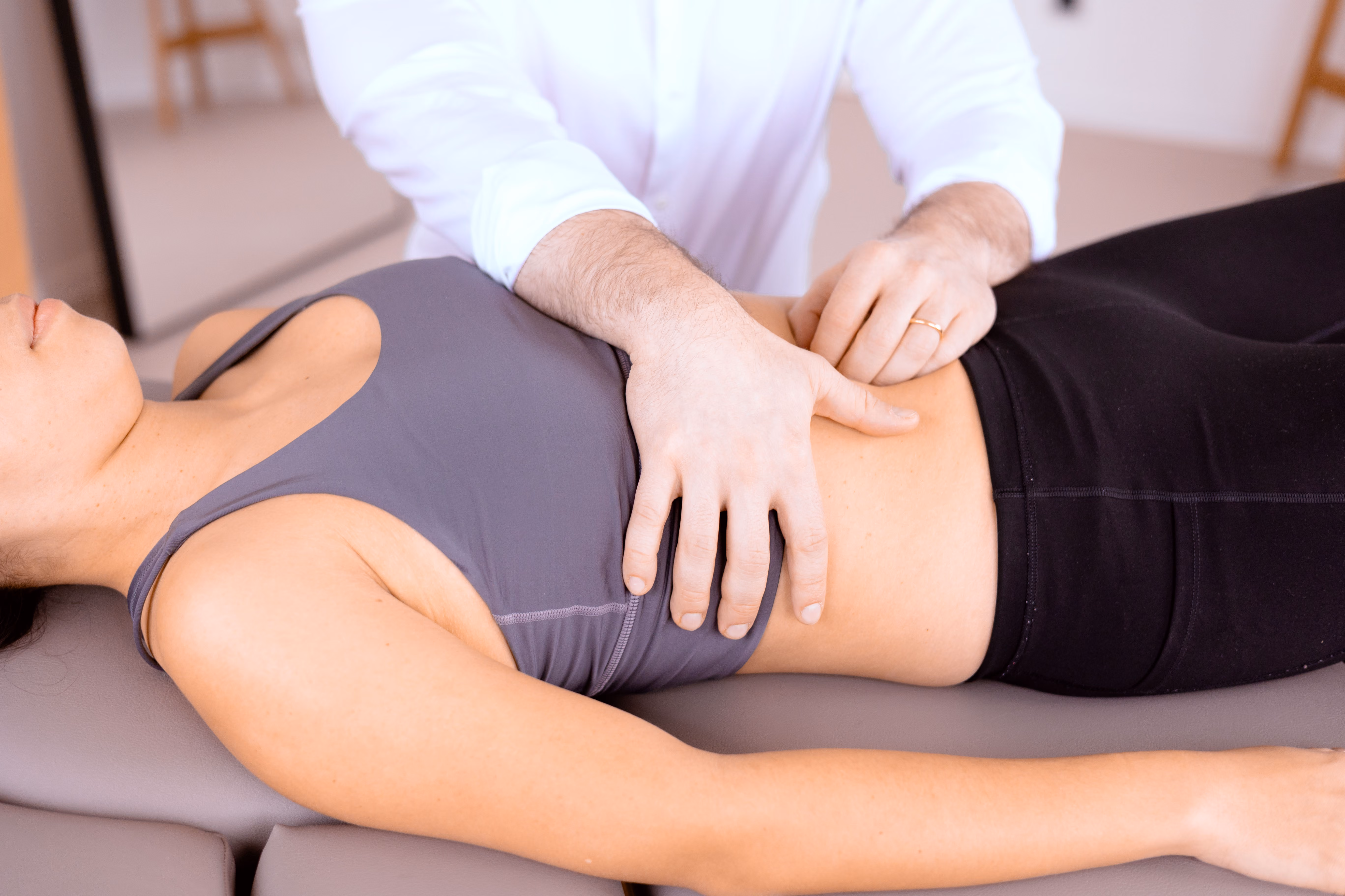 Osteopathische Behandlung am Bauch einer liegenden Patientin