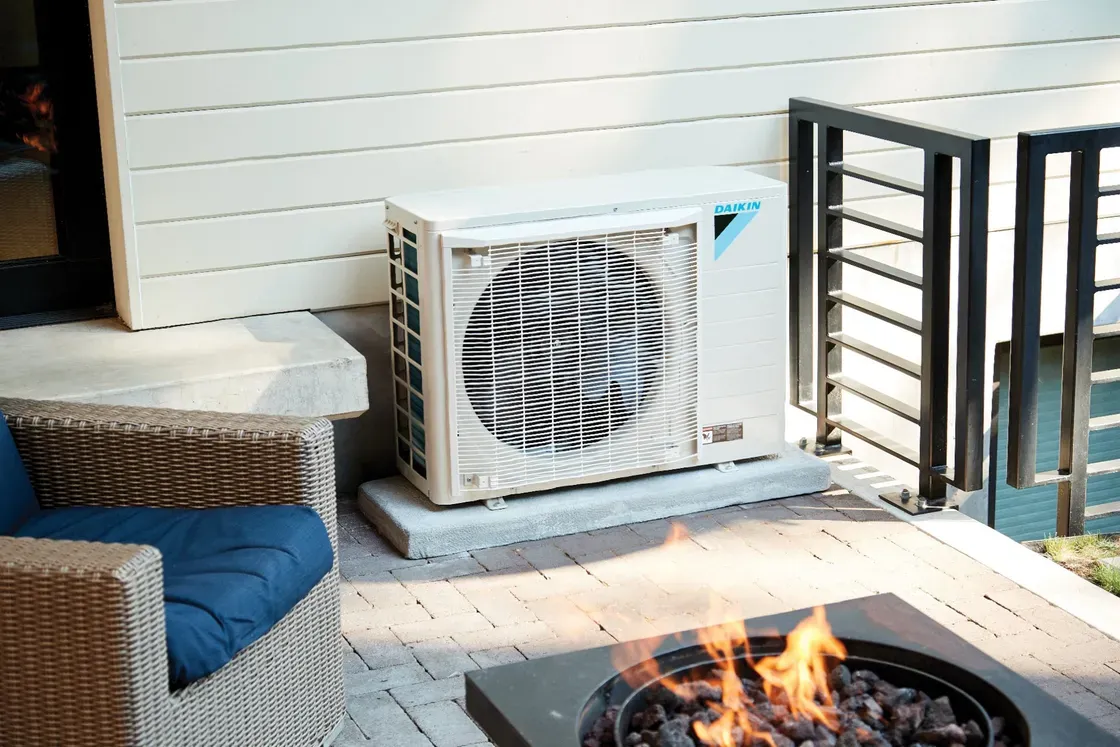 Daikin air conditioner unit on patio with fire pit and wicker furniture